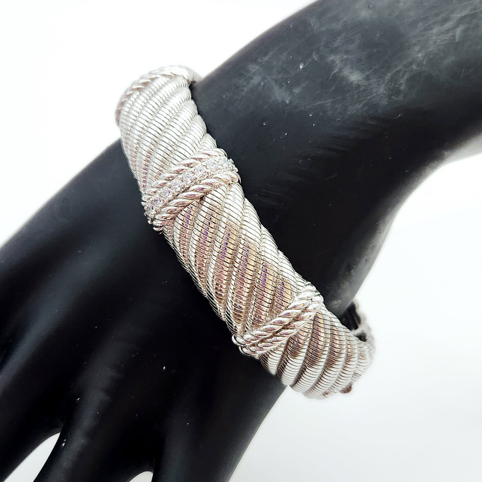 Judith Ripka Sterling & CZ Bracelet 78.1 Grams: A sterling silver twisted cable cuff bracelet by Judith Ripka featuring a cubic zirconia set central bar, weighing approximately 78.1 grams and measuring 2.5 inches in diameter, accompanied by a brand