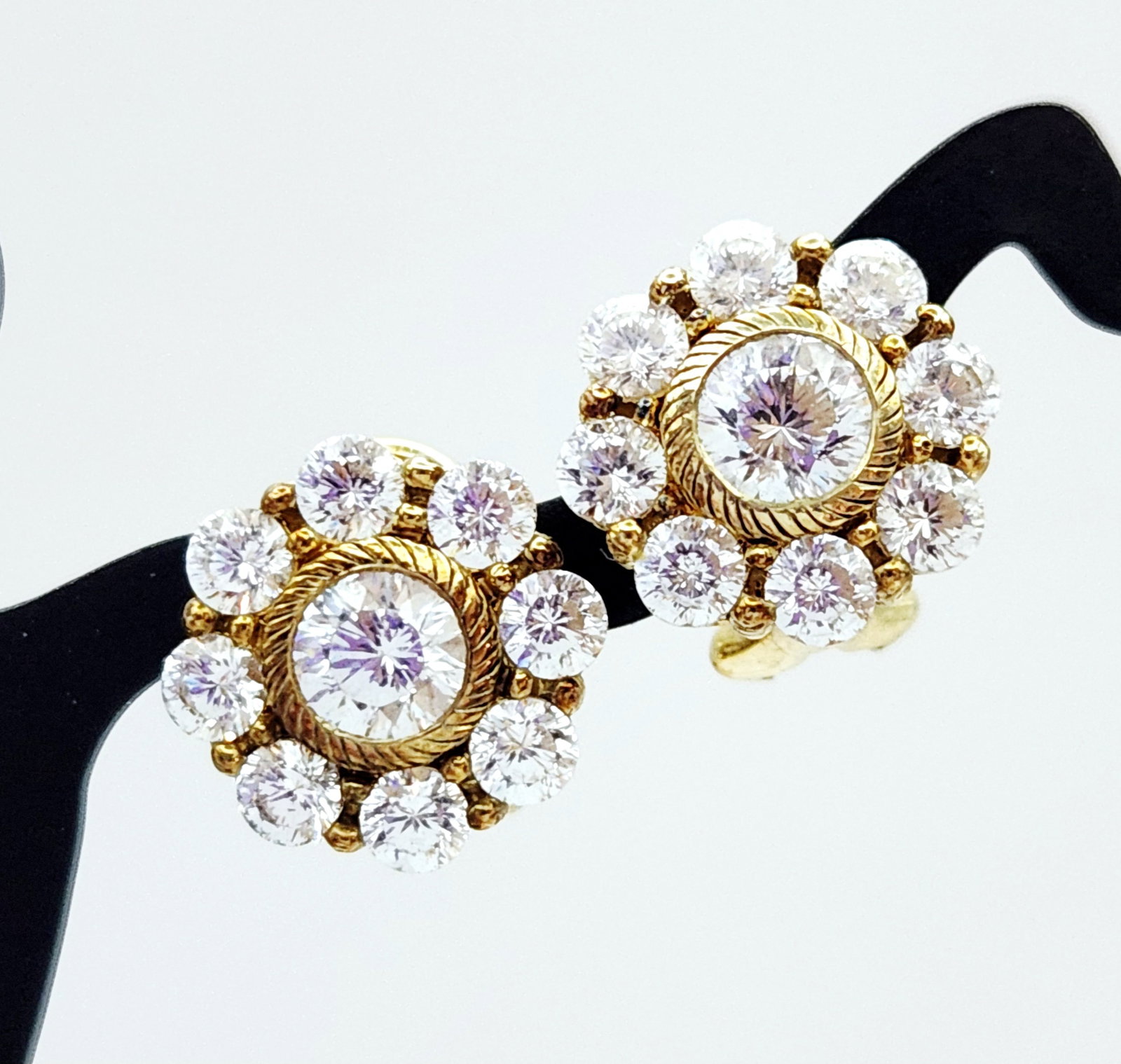 Judith Ripka Vermeil CZ Earrings 5.1 Grams: A pair of floral cluster earrings by Judith Ripka, crafted in gold-plated sterling silver. Each earring features a central round brilliant-cut colorless stone, which appears to be cubic zirconia, fram