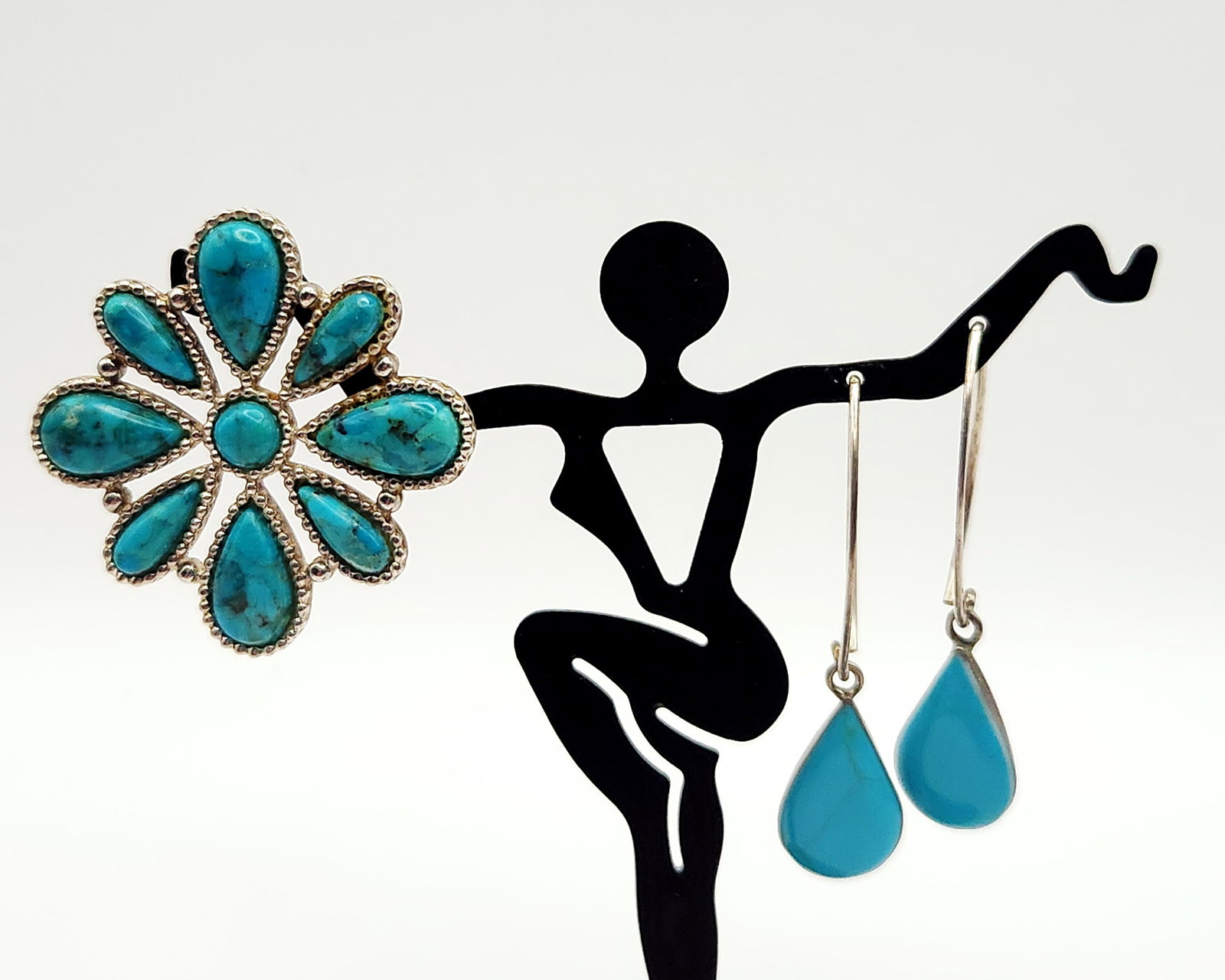 Sterling Turquoise Jewelry 13.6 Grams: This jewelry group consists of a flower-shaped pendant and a pair of drop earrings. The pendant is designed in a Native American style, featuring a central round turquoise cabochon surrounded by nine