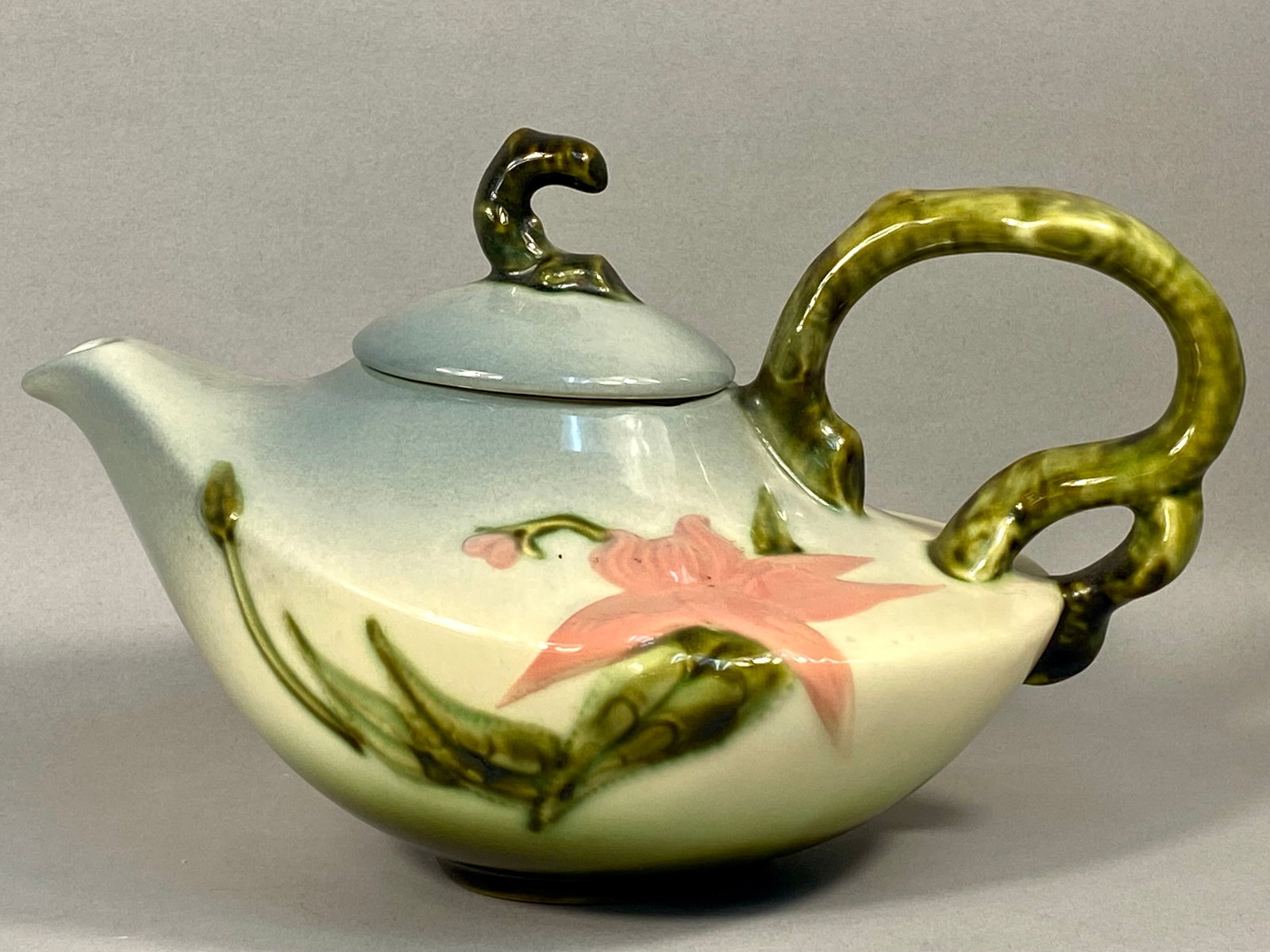 Hull Pottery Woodland Pattern Teapot and Lid Model W-26: A molded earthenware teapot with a matching lid produced by the Hull Pottery Company in the Woodland pattern. The vessel features a low-slung, organic form with a matte-shaded glaze that transitions f