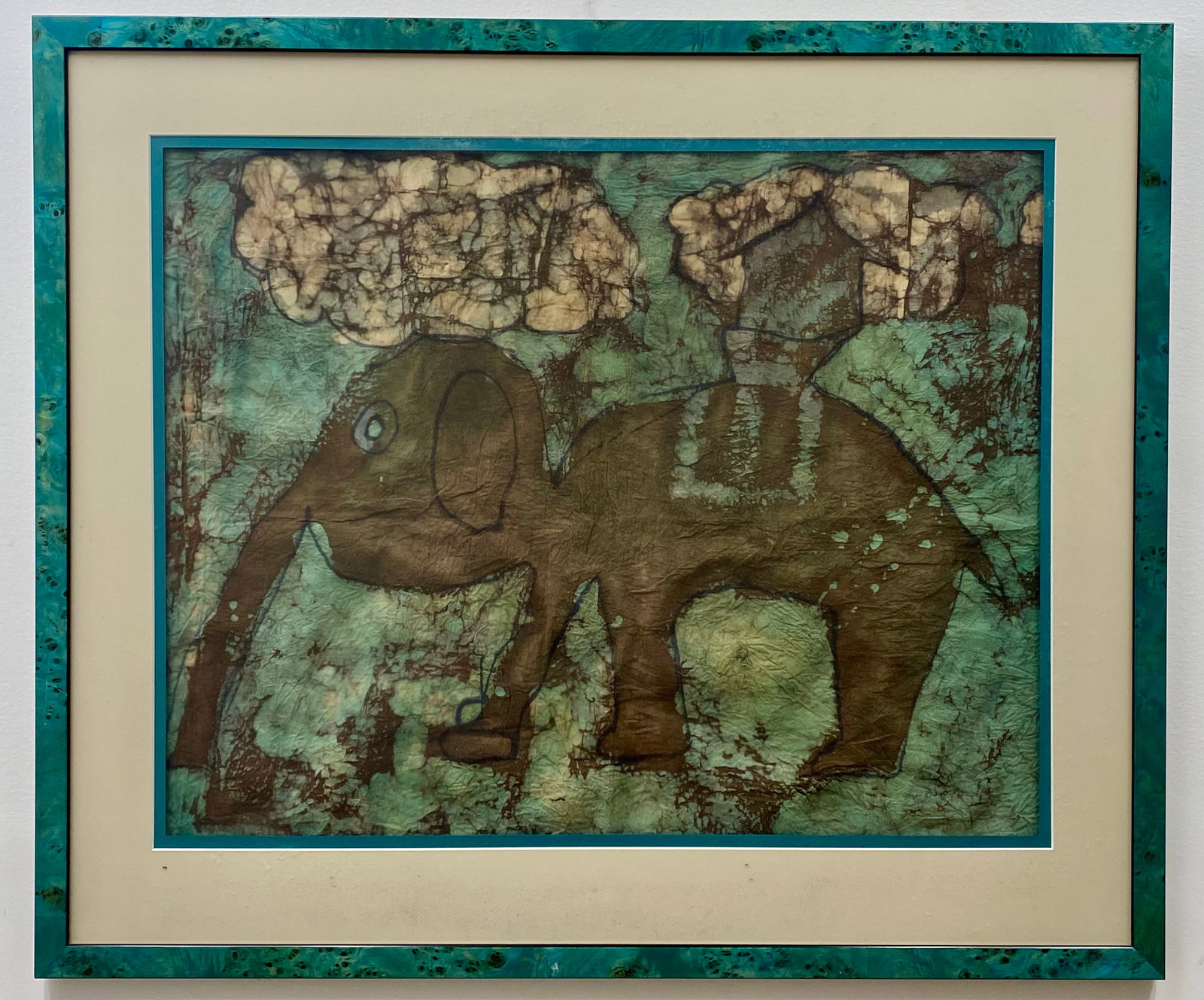 Modernist Batik Textile of an Elephant in a Landscape: This is a framed textile artwork executed in the batik wax-resist dyeing technique on fabric. The composition depicts a stylized elephant in profile, rendered in a palette of brown, against a variegat