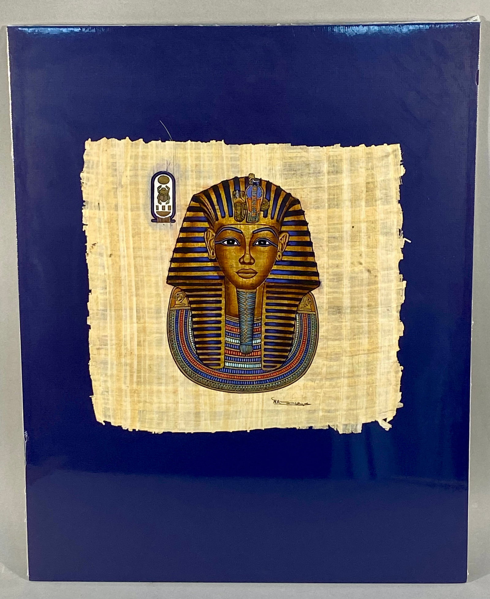 MA (Egyptian), Tutankhamun Mask Papyrus Painting (Signed): This modern Egyptian painting is executed in gouache and metallic gold pigments on a papyrus support. The artwork depicts the funerary mask of Pharaoh Tutankhamun in a traditional style, featuring the
