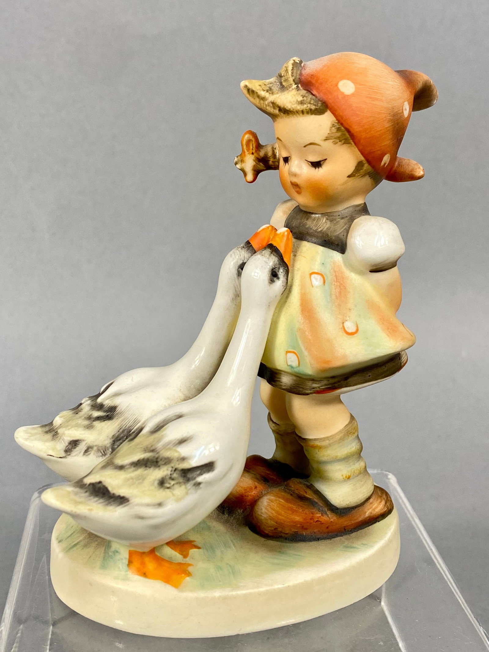 Goebel Hummel Goose Girl Porcelain Figurine Model 47 3/0: This Goebel Hummel porcelain figurine, titled Goose Girl, is model number 47. The piece depicts a young girl in traditional Bavarian attire, including a red polka-dot headscarf and a patterned apron,