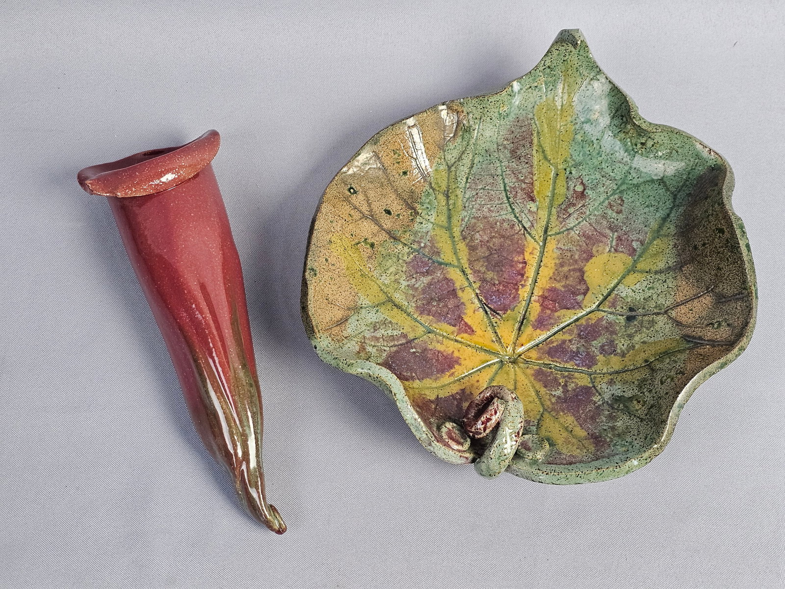 Two Pieces of Studio Pottery Including a Leaf-Shaped Bowl and a Horn-Shaped Wall Pocket: This lot consists of two distinct pieces of hand-formed studio pottery stoneware. The first item is a shallow bowl modeled as a large serrated leaf. It features an integral curled handle at the stem a