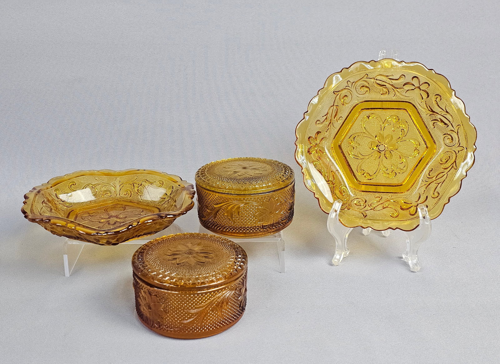 A Set of Amber Pressed Glass Bowls and Lidded Jars in the Sandwich Pattern: A set of decorative amber pressed glass items, attributed to Indiana Glass for the Tiara Exclusives line in the Sandwich pattern. The collection consists of bowls and lidded jars. Bowl diameter: 6 in