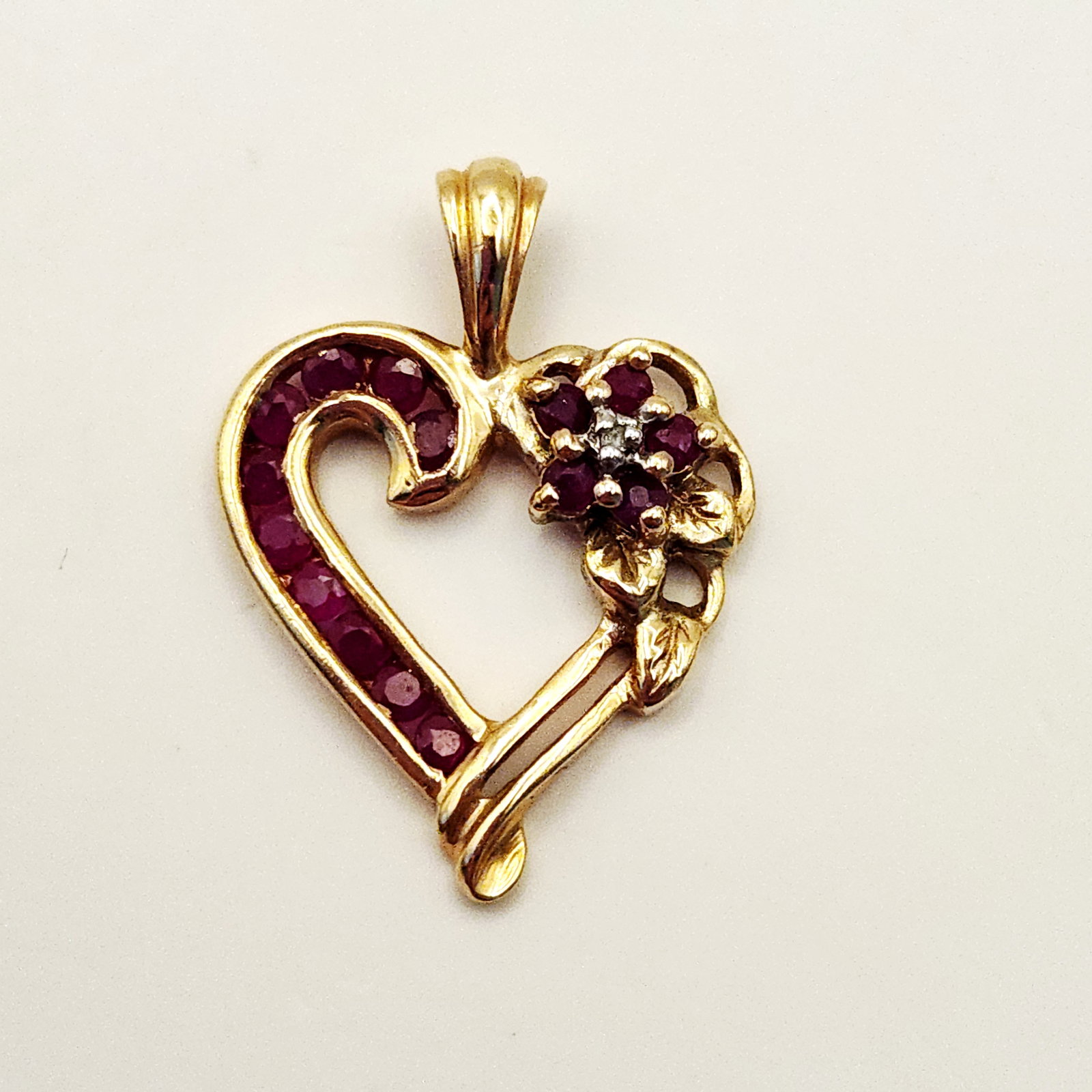 10K Gold Heart Pendant 2.5 Grams: This 10 karat yellow gold heart-shaped pendant features an openwork design with a floral accent. On the reverse, the pendant is stamped with the characters CI and 10K. Weight: 2.5 grams Length: Approx