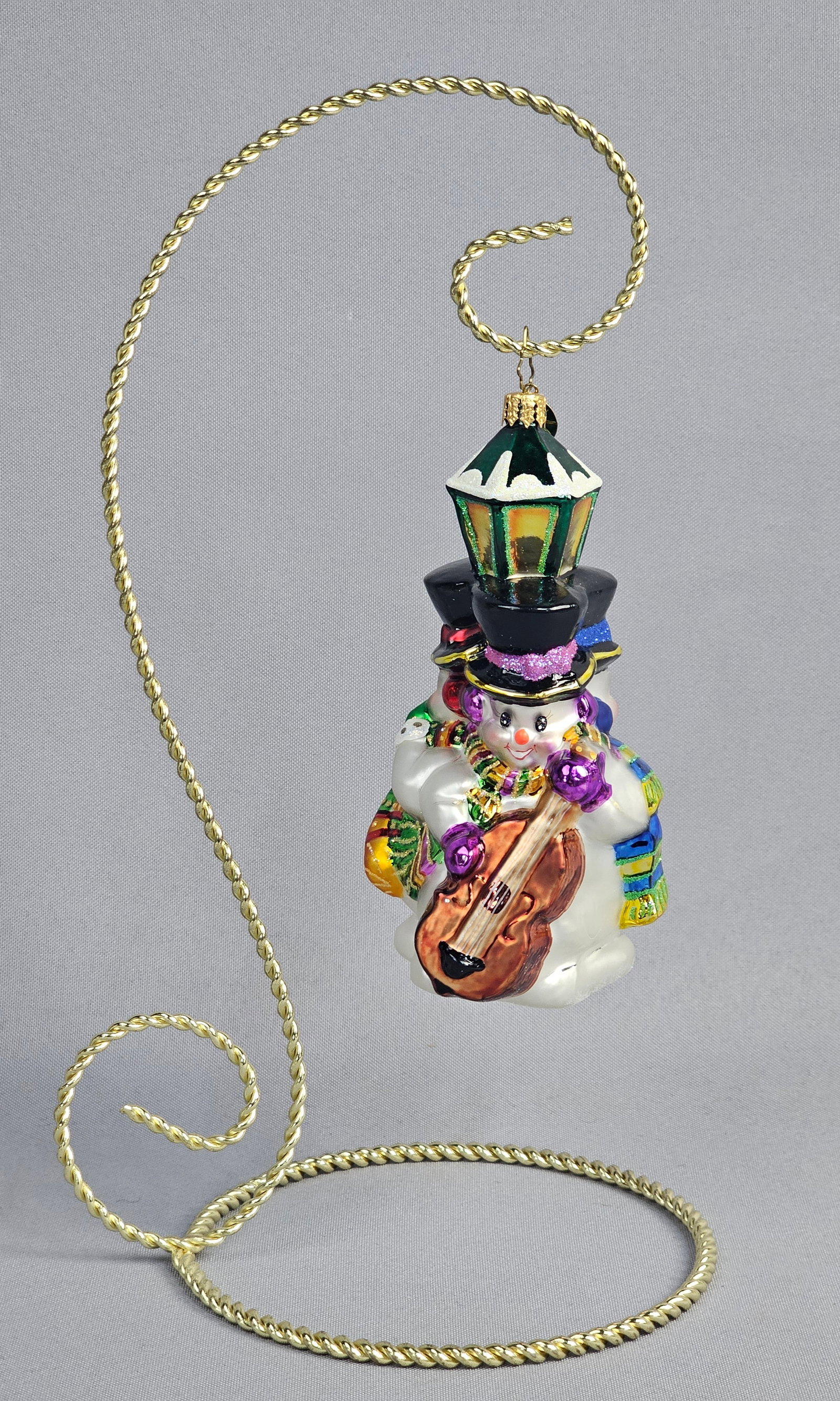 Christopher Radko Glass Musical Snowman Ornament: Stand not included. A mouth-blown, hand-painted glass ornament by Christopher Radko, featuring a festive musical group of three snowmen. The ornament is in excellent condition. There are no visible ch