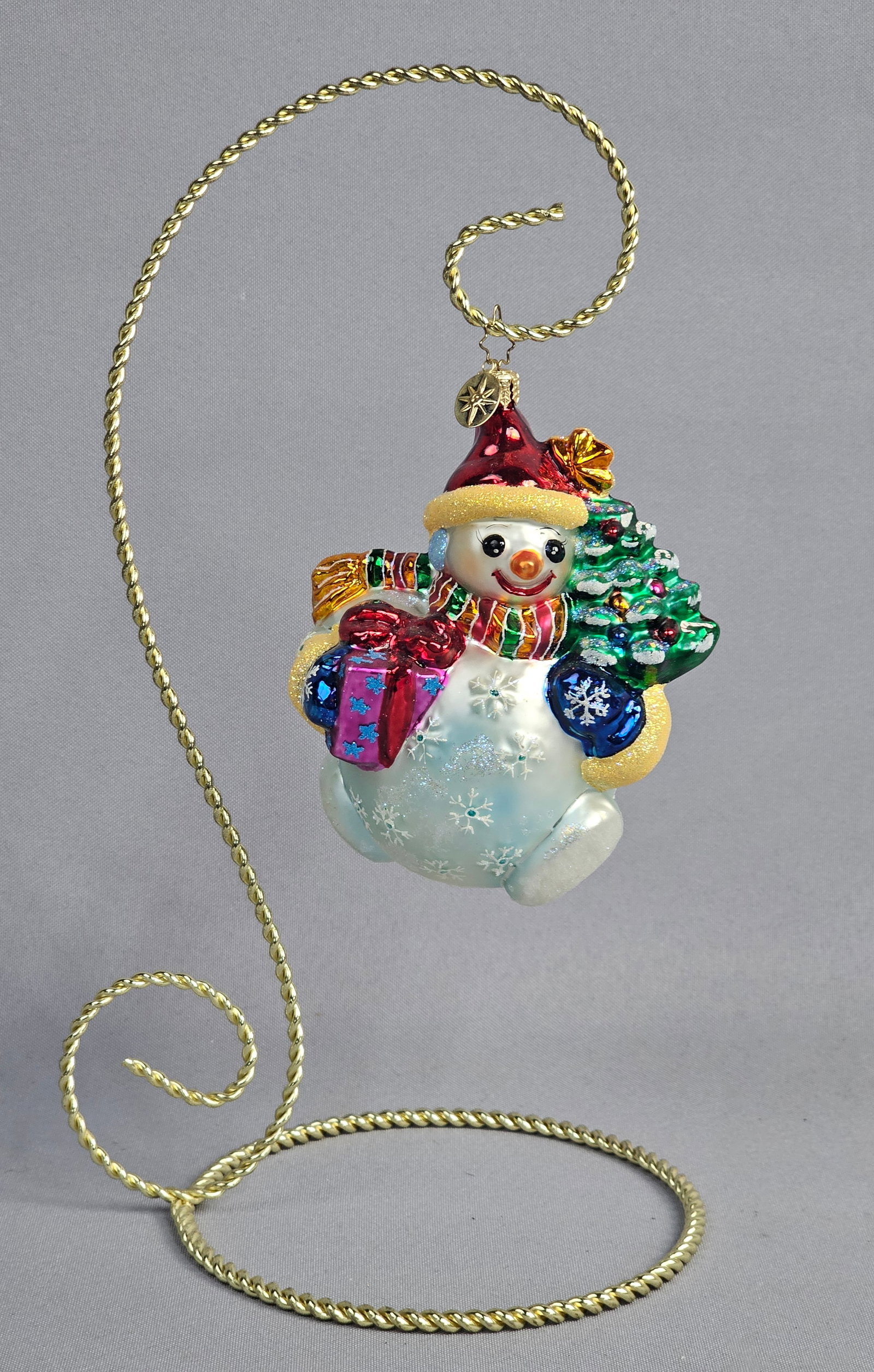 Christopher Radko Chubby Cheer Delight Snowman Ornament: Stand not included. This lot features a mouth-blown glass Christmas ornament by Christopher Radko, identified as the Chubby Cheer Delight snowman pattern. The figure is depicted wearing a red hat with