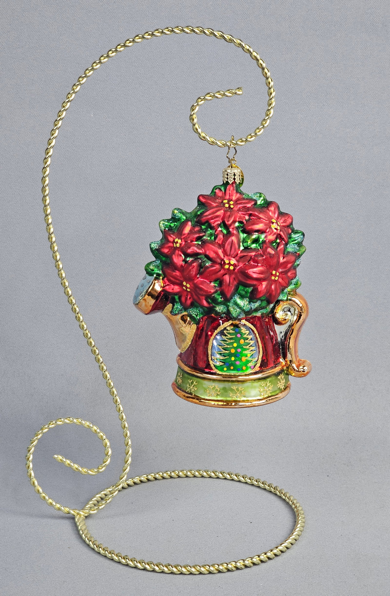 Christopher Radko Mouth-Blown Glass Poinsettia Watering Can Christmas Ornament: This mouth-blown and hand-painted glass holiday ornament is produced by Christopher Radko. The piece is designed as a red watering can overflowing with red poinsettia blossoms accented with green glit