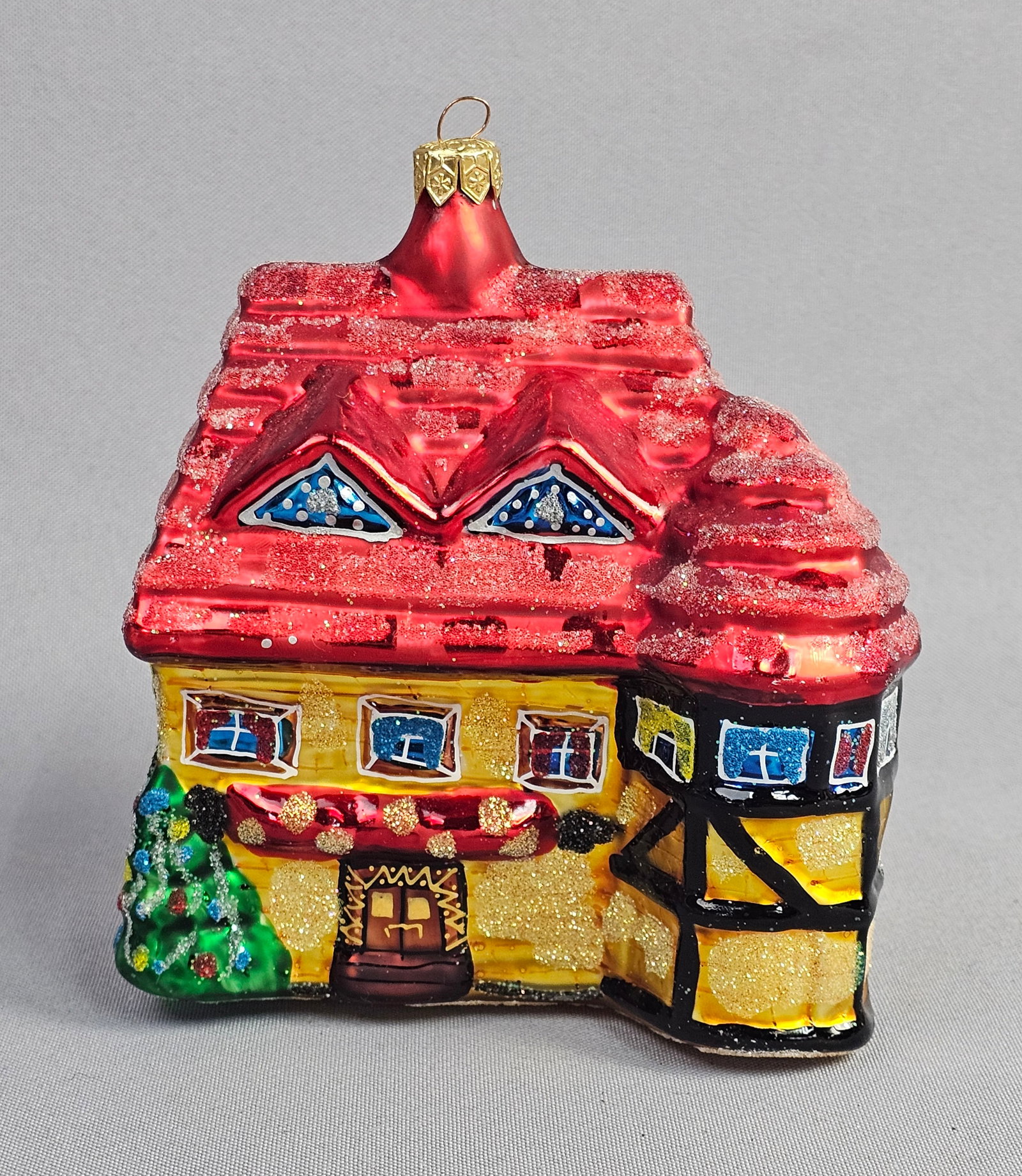 Polish Mouth-Blown Glass House Christmas Ornament, Attributed to Christopher Radko: This figural Christmas ornament is attributed to Christopher Radko and depicts a multi-story European-style cottage or chalet. The object is crafted from mouth-blown glass. It features a tiered red ro