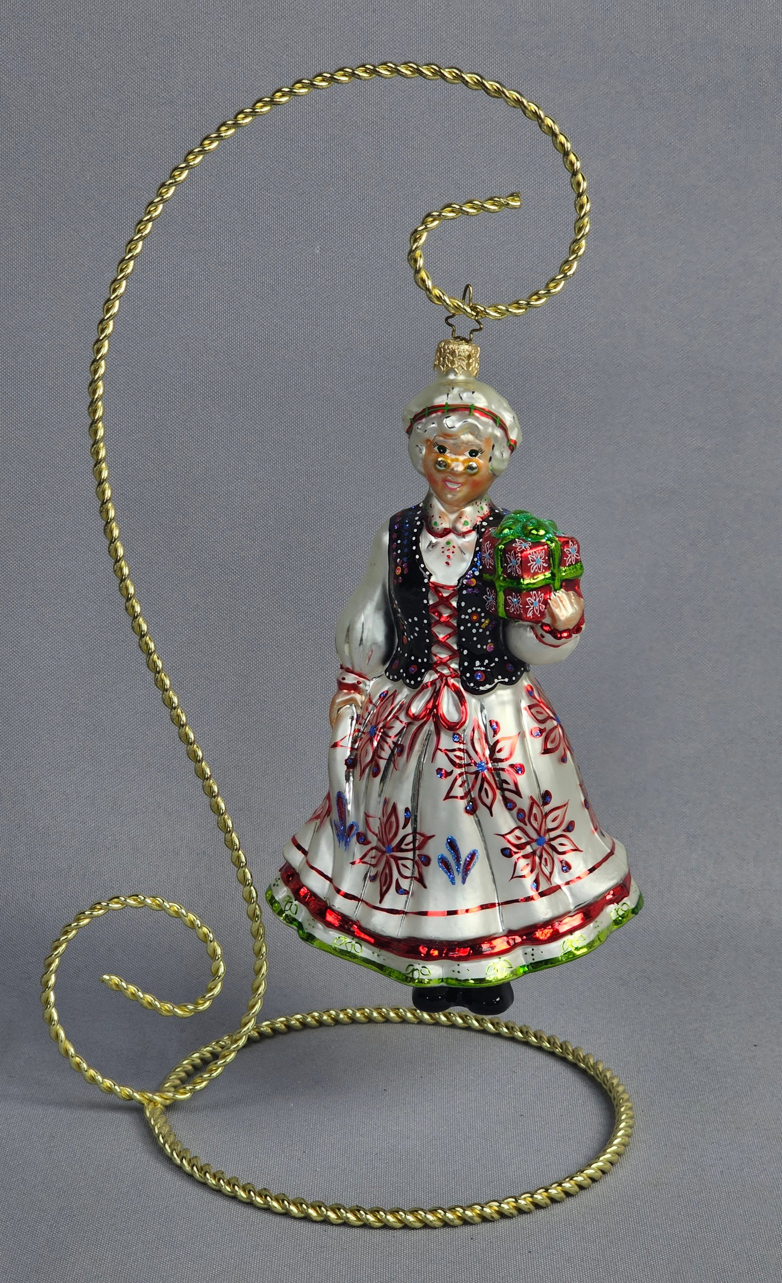 Christopher Radko Mrs. Claus Krak??w Polish Folk Costume Glass Christmas Ornament with Stand: A Christopher Radko hand-blown glass Christmas ornament depicting Mrs. Claus in traditional Kraków female folk costume. The figure features a white dress with hand-painted red and blue floral s