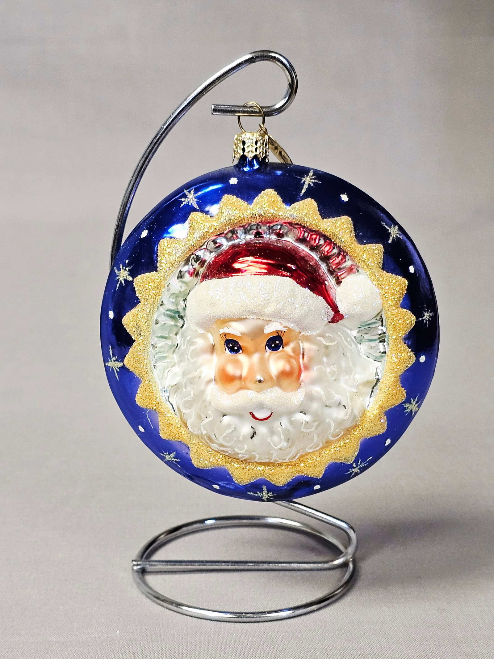 Christopher Radko Santa Star Shine Glass Reflector Ornament: Stand not included. This hand-blown glass Christmas ornament is produced by Christopher Radko, identified by the signature star-shaped metal charm and the decorative metal cap embossed with a holly le