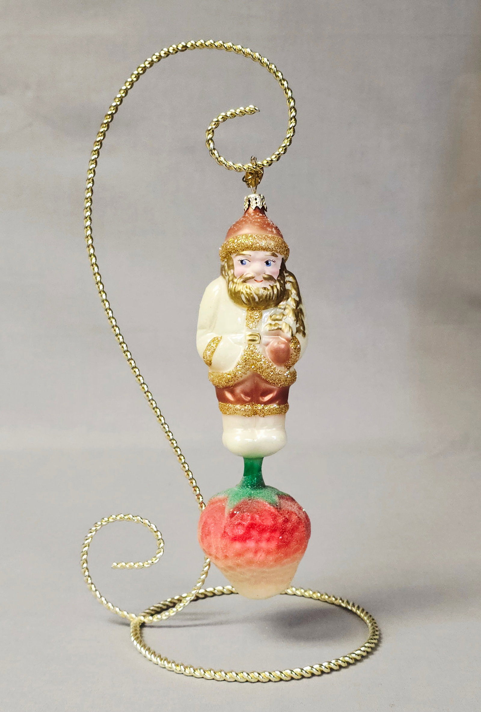 Christopher Radko Glass Ornament Santa on Strawberry: Stand not included. This is a large, hand-blown glass figural Christmas ornament by Christopher Radko. The design features a Santa Claus figure standing atop an oversized strawberry. The ornament is i