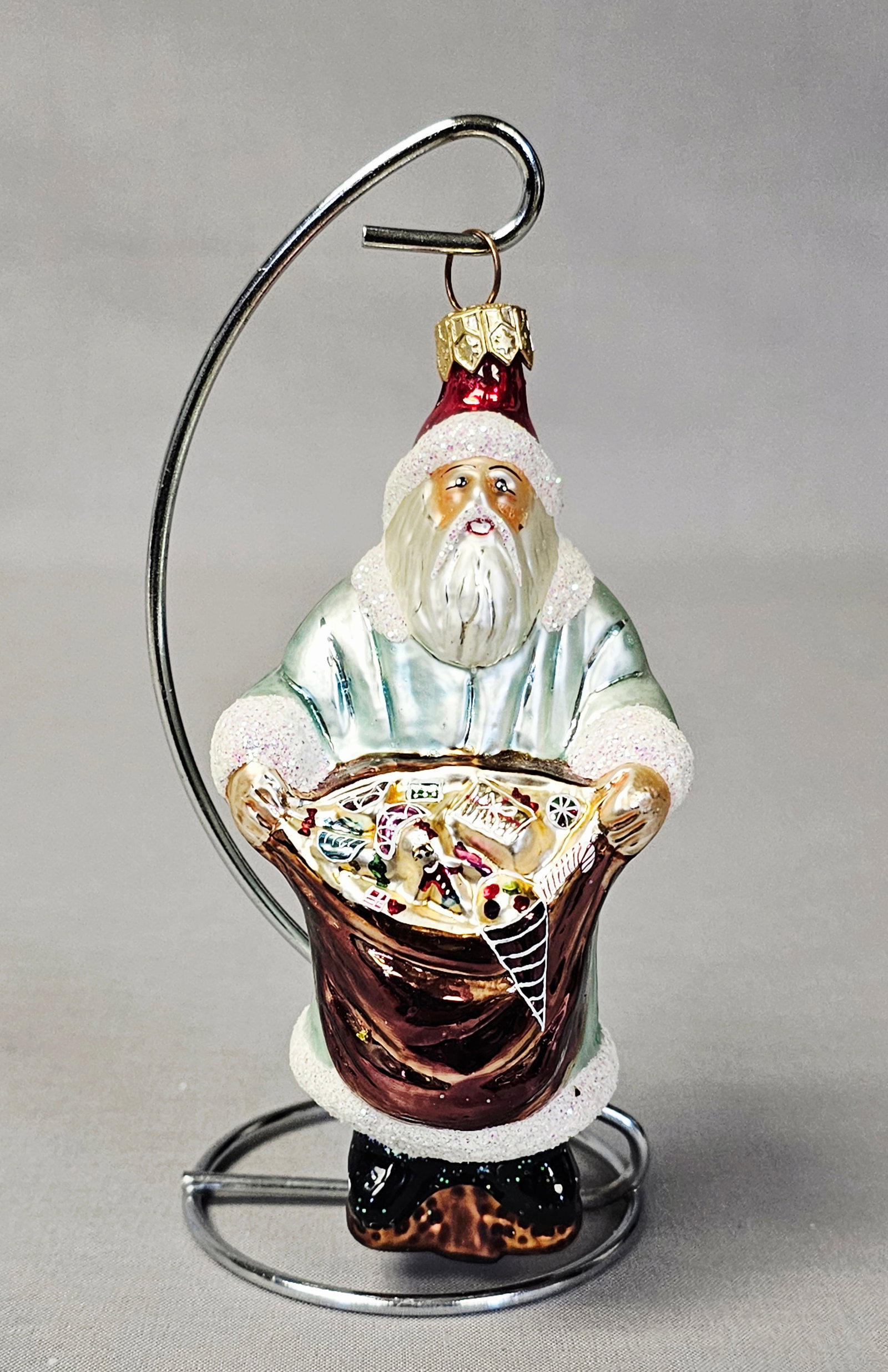 Christopher Radko Glass Santa Claus with Sack Ornament: Stand not included. This mouth-blown and hand-painted glass Christmas ornament depicts a full-figure Santa Claus holding a gift sack. The ornament is in very good condition with no visible cracks, chi