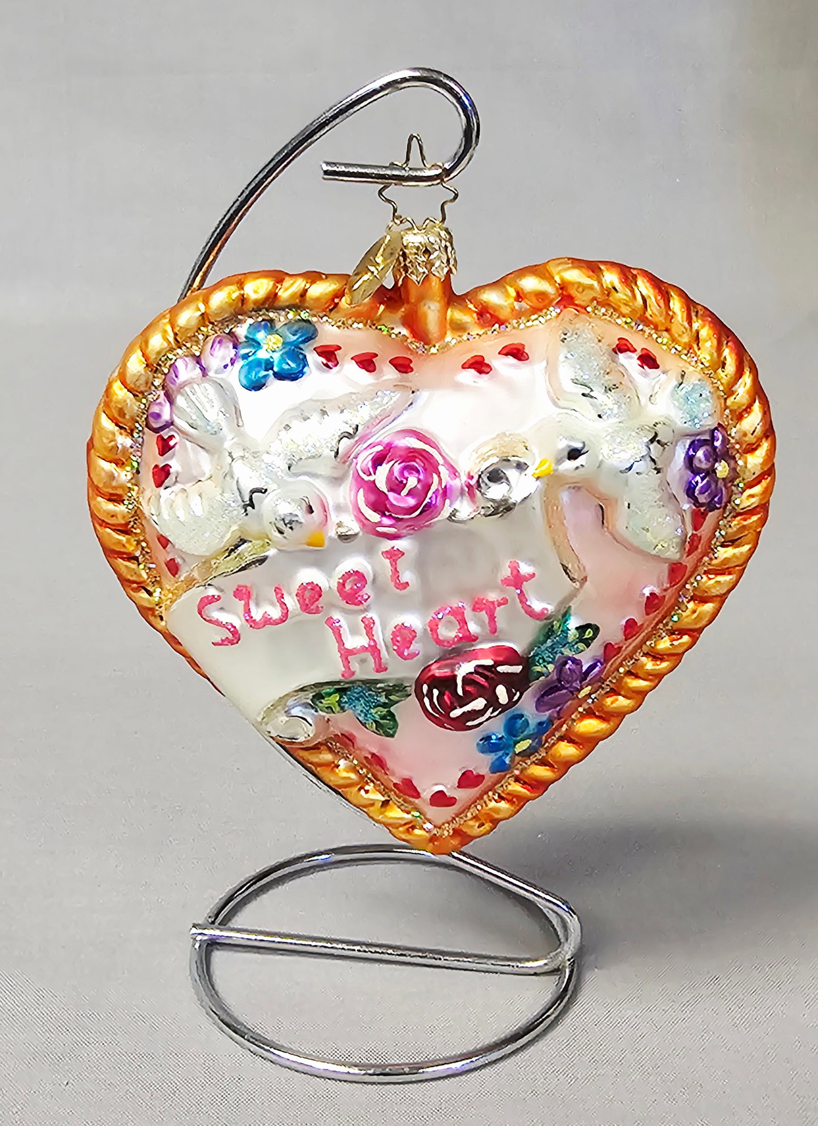 Christopher Radko Sweet Heart Glass Heart Ornament: Stand not included. This large, heart-shaped holiday ornament is a mouth-blown glass creation by Christopher Radko. The piece features an opalescent white ground decorated with three-dimensional, high