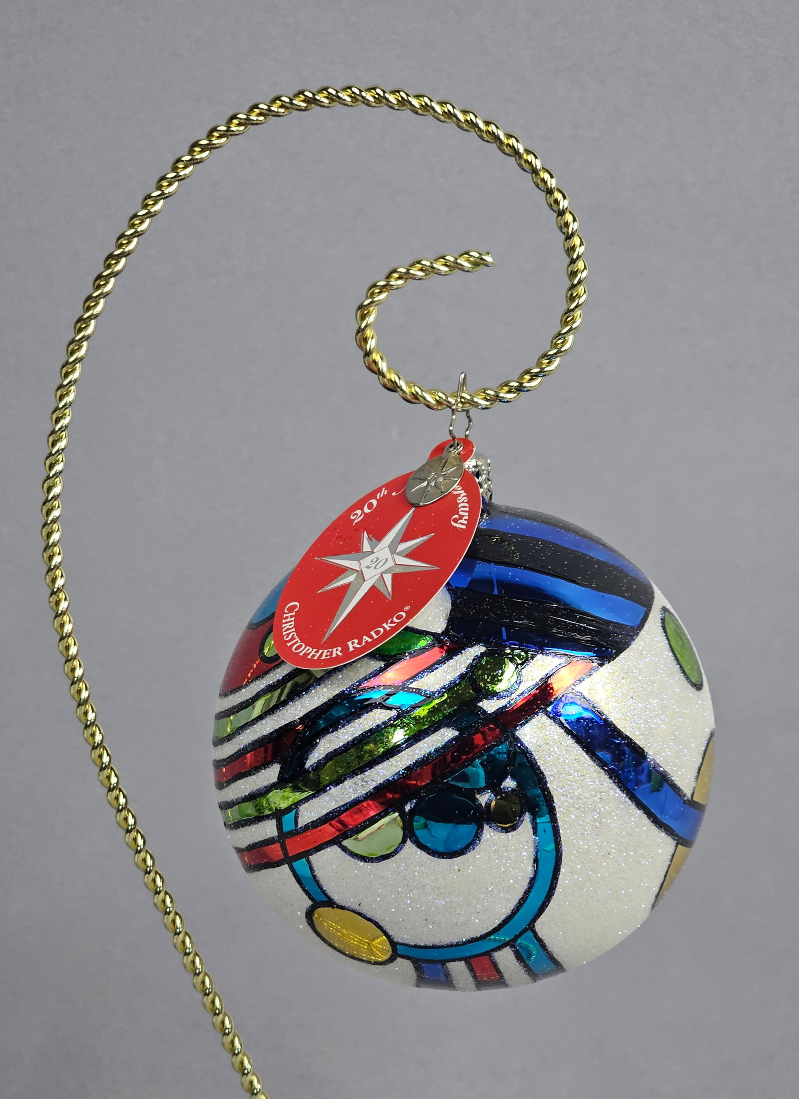 Christopher Radko 20th Anniversary Commemorative Glass Ornament (2006): Christopher Radko. Hand-blown and hand-painted glass ball ornament. This commemorative 20th Anniversary piece, dated 2006, features an abstract modernist design with circular motifs and sweeping bands