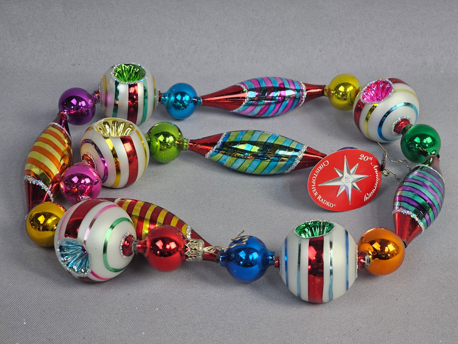 Three Christopher Radko 20th Anniversary Hand Blown Glass Bead Garlands: A trio of individual hand-blown glass bead garlands produced by Christopher Radko to commemorate the company's 20th anniversary. Each strand features an assortment of hand-painted mercury glass beads 