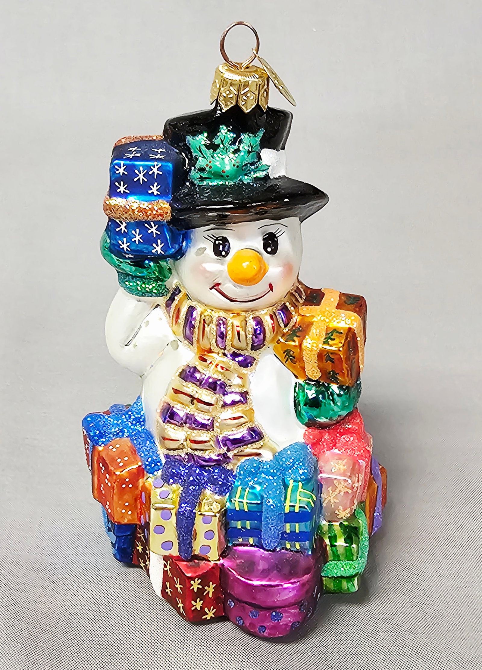 Christopher Radko Snowy & Bright Snowman Glass Ornament: Stand not included. This hand-blown glass Christmas ornament is identified as the Snowy and Bright model by designer Christopher Radko. The ornament depicts a jovial snowman with a hand-painted face, 