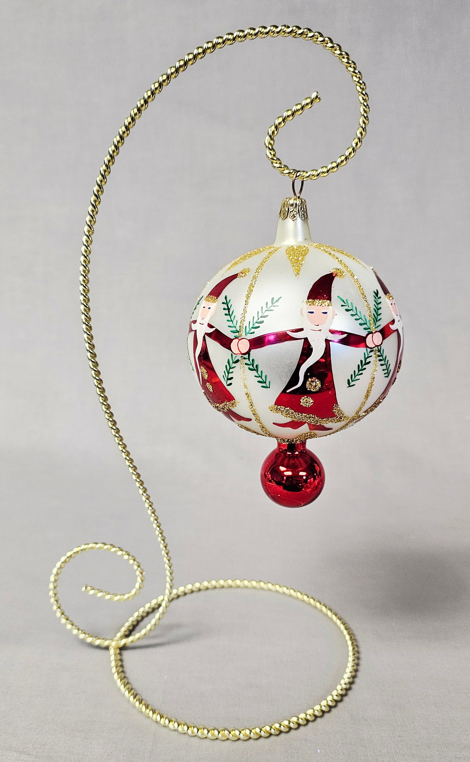 Christopher Radko Hand-Blown Glass Ornament: Stand not included. A hand-blown and hand-painted glass Christmas ornament by Christopher Radko. The ornament features a spherical main body with a white pearlescent finish, decorated with a motif dep