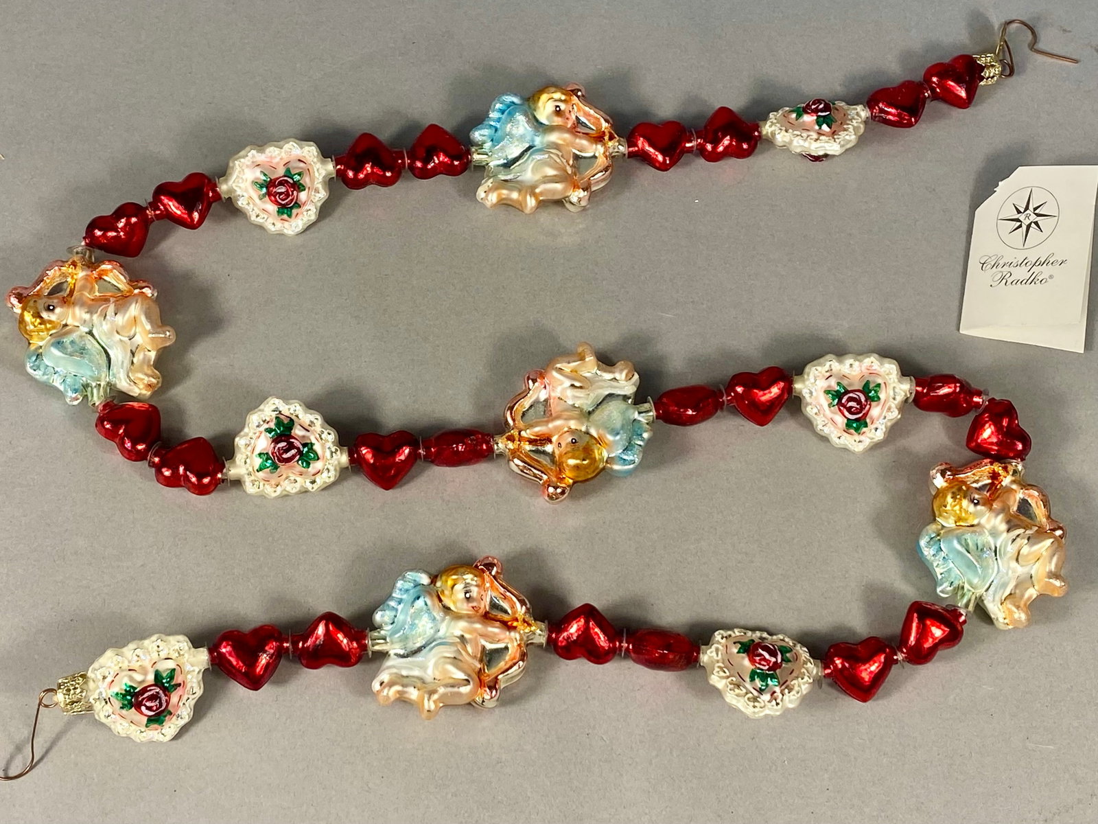 Radko In Love's Pursuit Hand-Blown Glass Garland: This Christopher Radko hand-blown glass decorative garland is titled In Love's Pursuit, identified by item number 02-0394-0. The garland is constructed from silvered and hand-painted glass components 