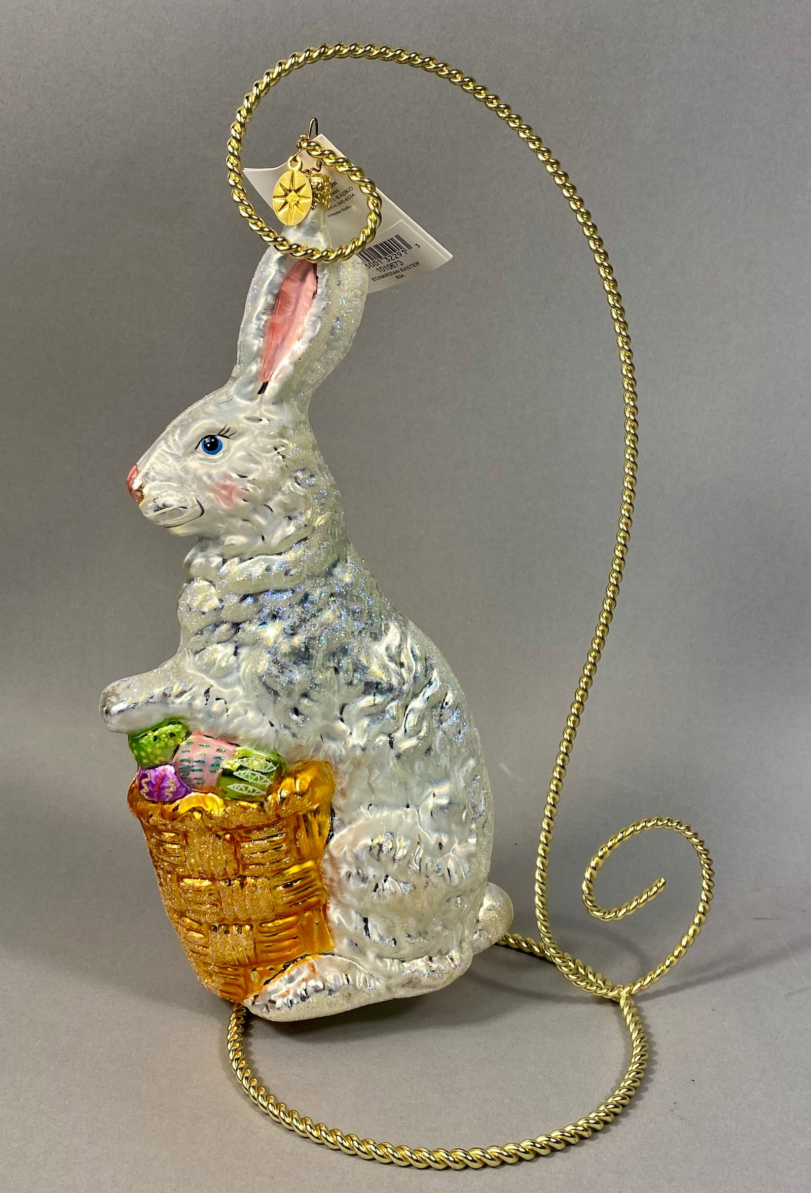 Radko Edwardian Easter Blown Glass Bunny Ornament: Hand-painted blown glass ornament by Christopher Radko, titled Edwardian Easter. The ornament depicts a standing white rabbit with a textured, iridescent, and glitter-flecked finish. The piece is topp