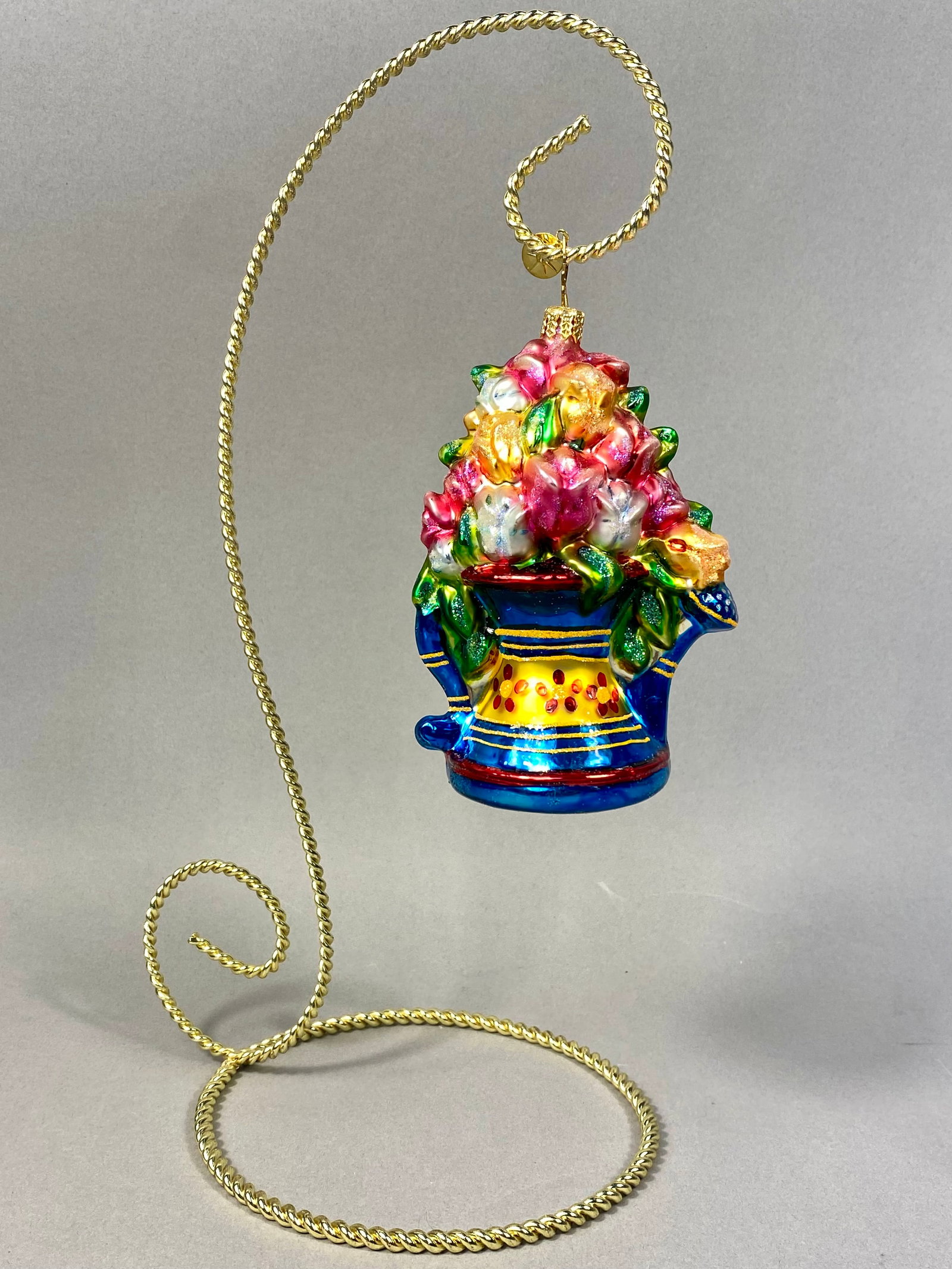 Radko Hand-Blown Glass Floral Pitcher Holiday Ornament: This hand-blown glass holiday ornament is a Christopher Radko design, featuring the form of a watering can overflowing with a multi-colored floral bouquet. Fine glitter highlights are applied througho