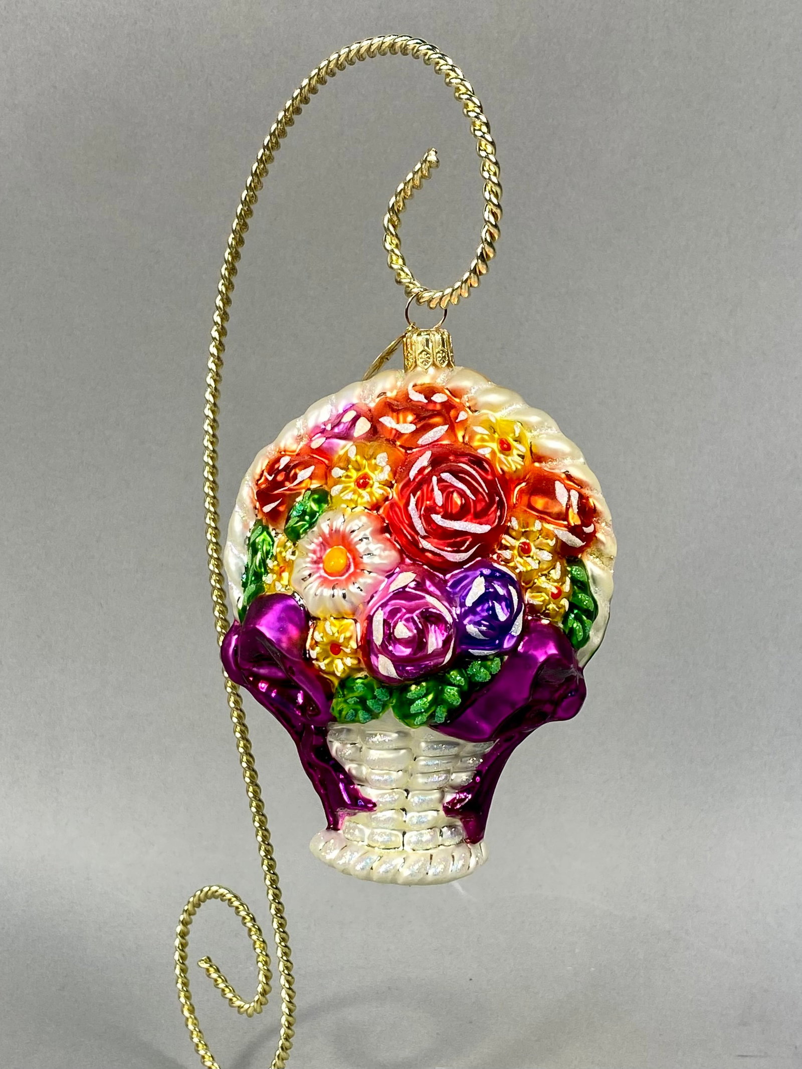 Radko Flower Power Glass Flower Basket Christmas Ornament: This is a hand-blown glass Christmas ornament manufactured by Christopher Radko, featuring the Flower Power floral basket design. The ornament depicts a pearlescent white basket with a molded wicker t