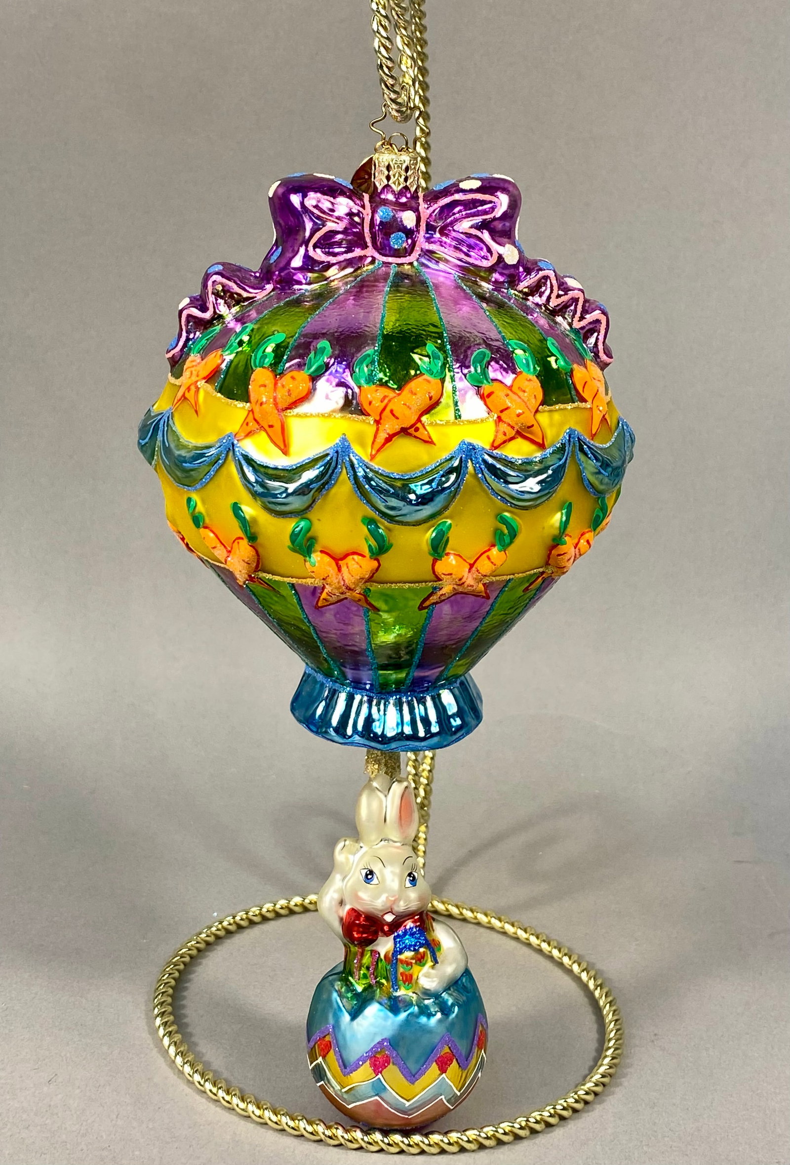 Radko Breezy Billy Easter Hot Air Balloon Glass Ornament: A large, two-part pendant glass ornament from the Christopher Radko collection, specifically the Breezy Billy pattern. This holiday ornament is crafted from hand-blown glass and features a whimsical h