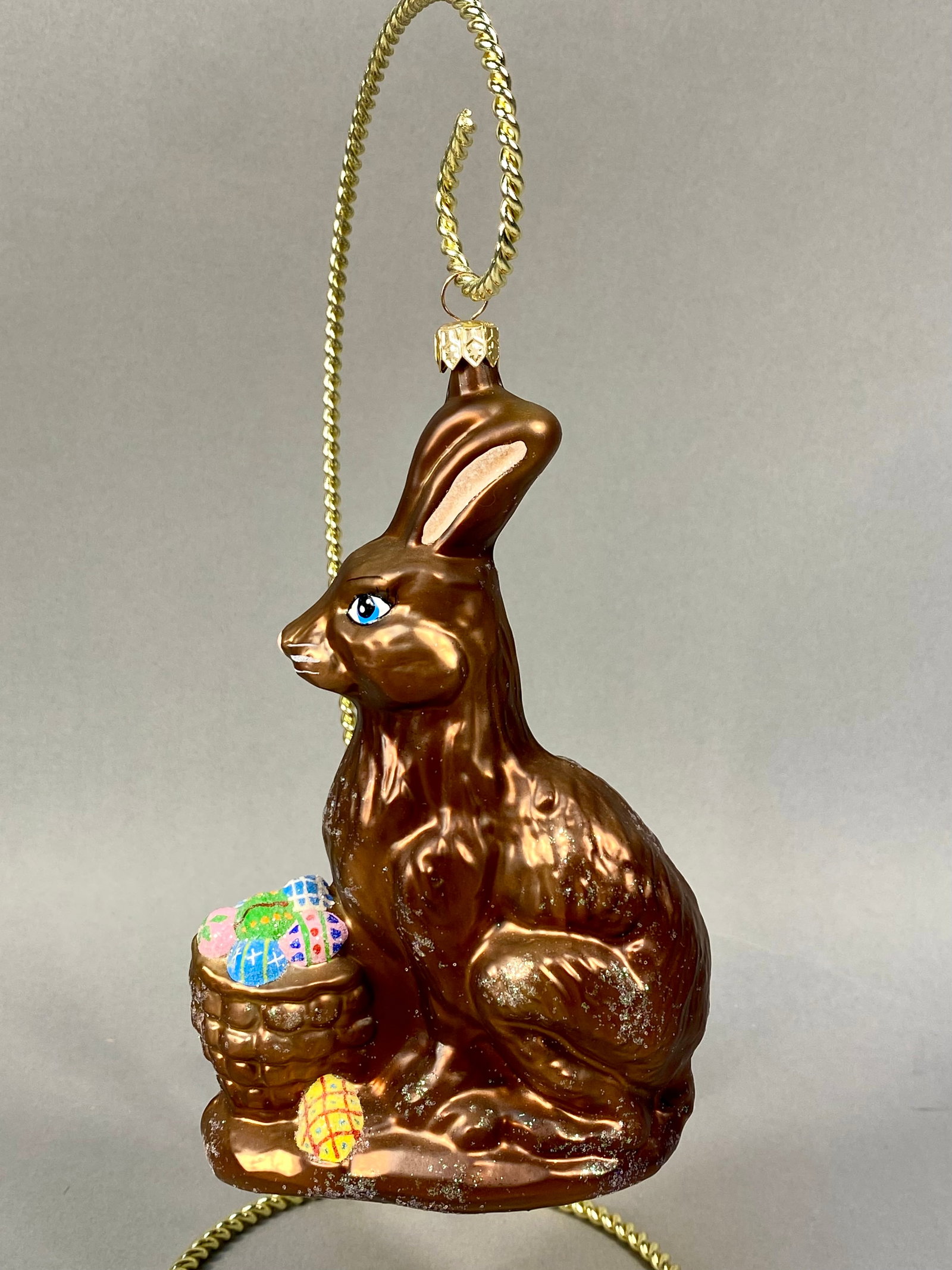 Radko Large Hand-Blown Glass Chocolate Bunny Ornament: A large, hand-blown glass holiday ornament by Christopher Radko, designed as a seated Easter bunny. The figure is finished in a lustrous, metallic chocolate brown glaze intended to resemble a foil-wra