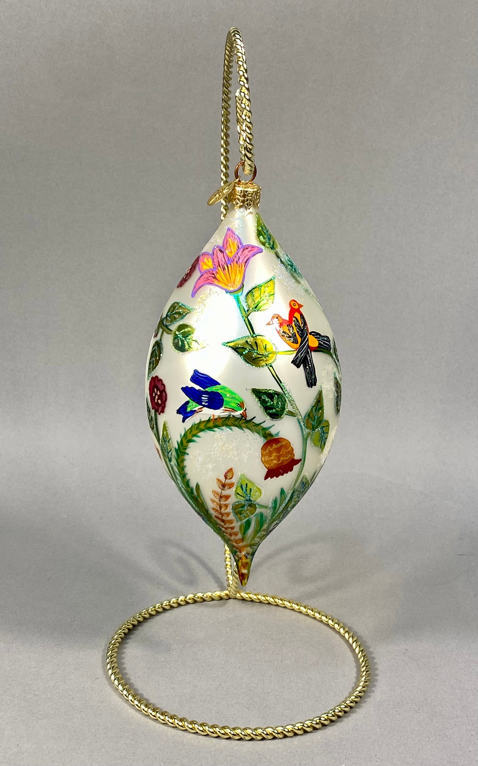 Radko Botanical Delight Hand-Painted Glass Ornament: Christopher Radko Botanical Delight hand-painted blown glass ornament. This large teardrop-shaped ornament features a pearlescent white base decorated with a detailed 360-degree nature scene. The orna