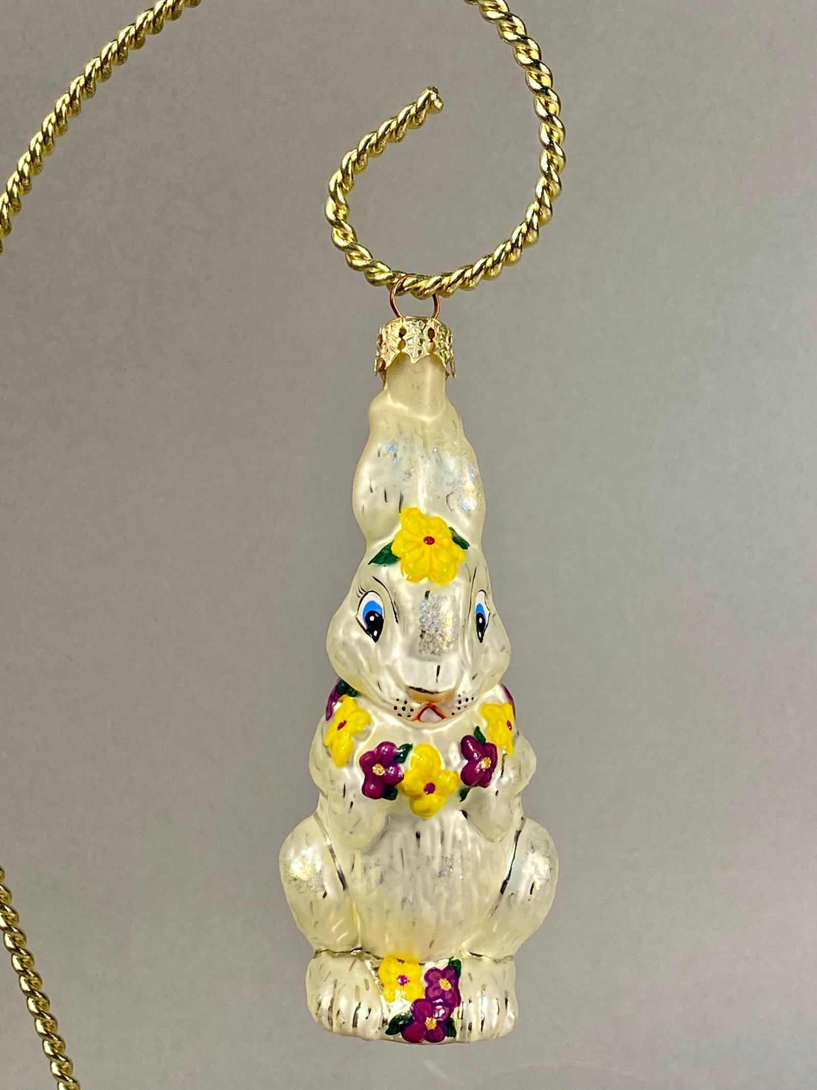 Radko Hoppy Holidays Bunny Ornament: **Stand Not Included** This mouth-blown glass ornament is a Christopher Radko figurine identified as the Hoppy Holidays bunny. The ornament is designed as a standing rabbit with a pearlescent white fi