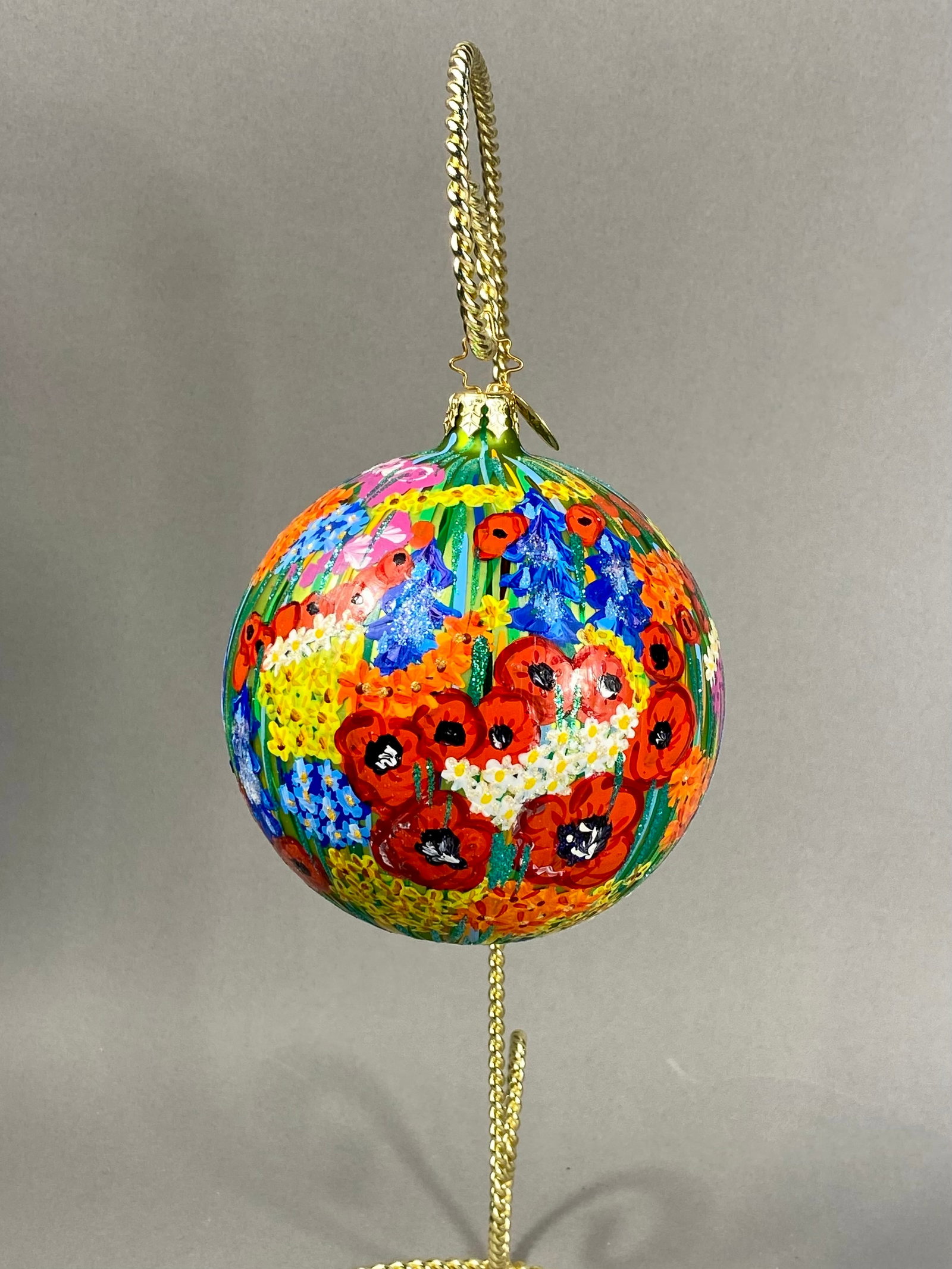 Radko Hand Painted Glass Wildflower Ornament: **Stand Not Included** A large spherical hand-blown glass ornament produced by Christopher Radko. The ornament features a hand-painted 360-degree scene depicting a dense wildflower meadow. The decorat