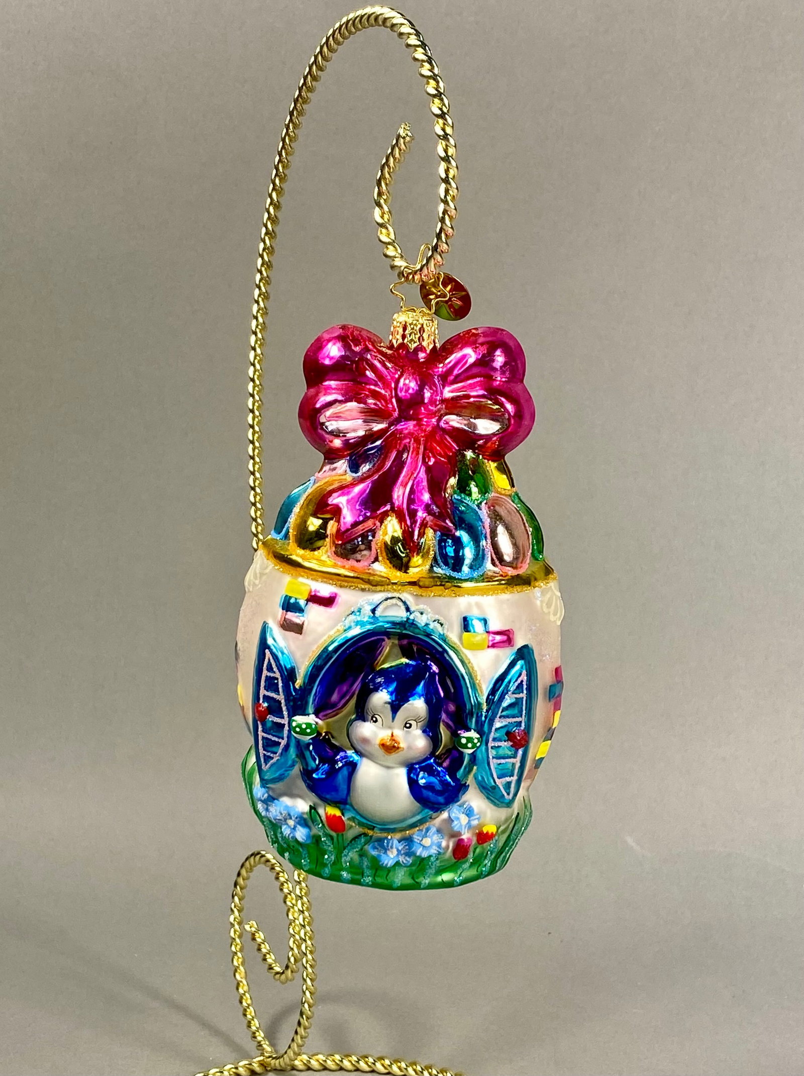 Radko Penny Glow Brightly Glass Penguin Diorama Egg Ornament: **Stand Not Included** A Christopher Radko mouth-blown and hand-painted glass holiday ornament, identified as the Penny Glow Brightly design. The ornament is shaped as a diorama egg with a central ope