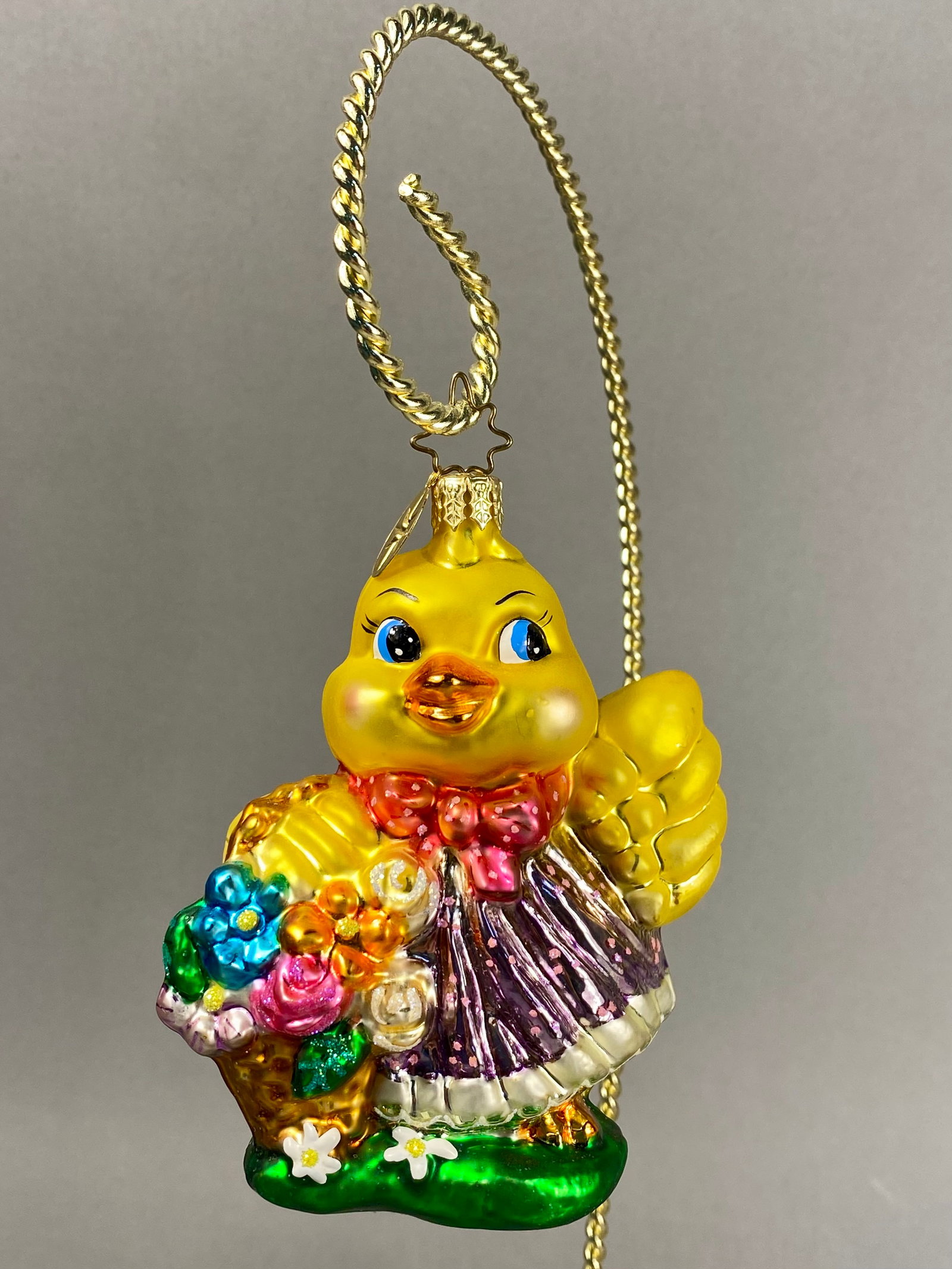 Radko Hand-Blown Glass Spring Chick Ornament: **Stand Not Included** Produced by Christopher Radko, this hand-blown glass figural ornament depicts a yellow chick dressed in a purple dress with pink glittered polka dots and a white scalloped trim.