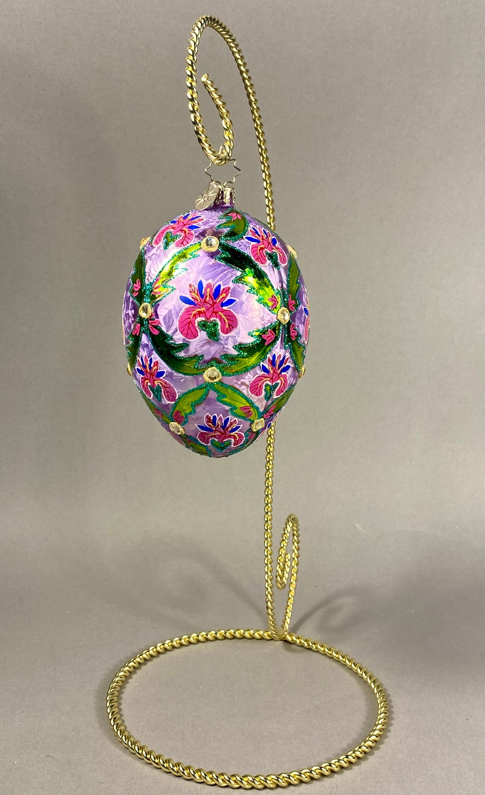 Christopher Radko Midnight Blossom Hand-Blown Glass Egg Ornament with Tabletop Stand: A Christopher Radko hand-blown glass ornament in the form of an egg, featuring the Midnight Blossom pattern. The piece is crafted with a lavender background exhibiting a crystalline ice-textured finis