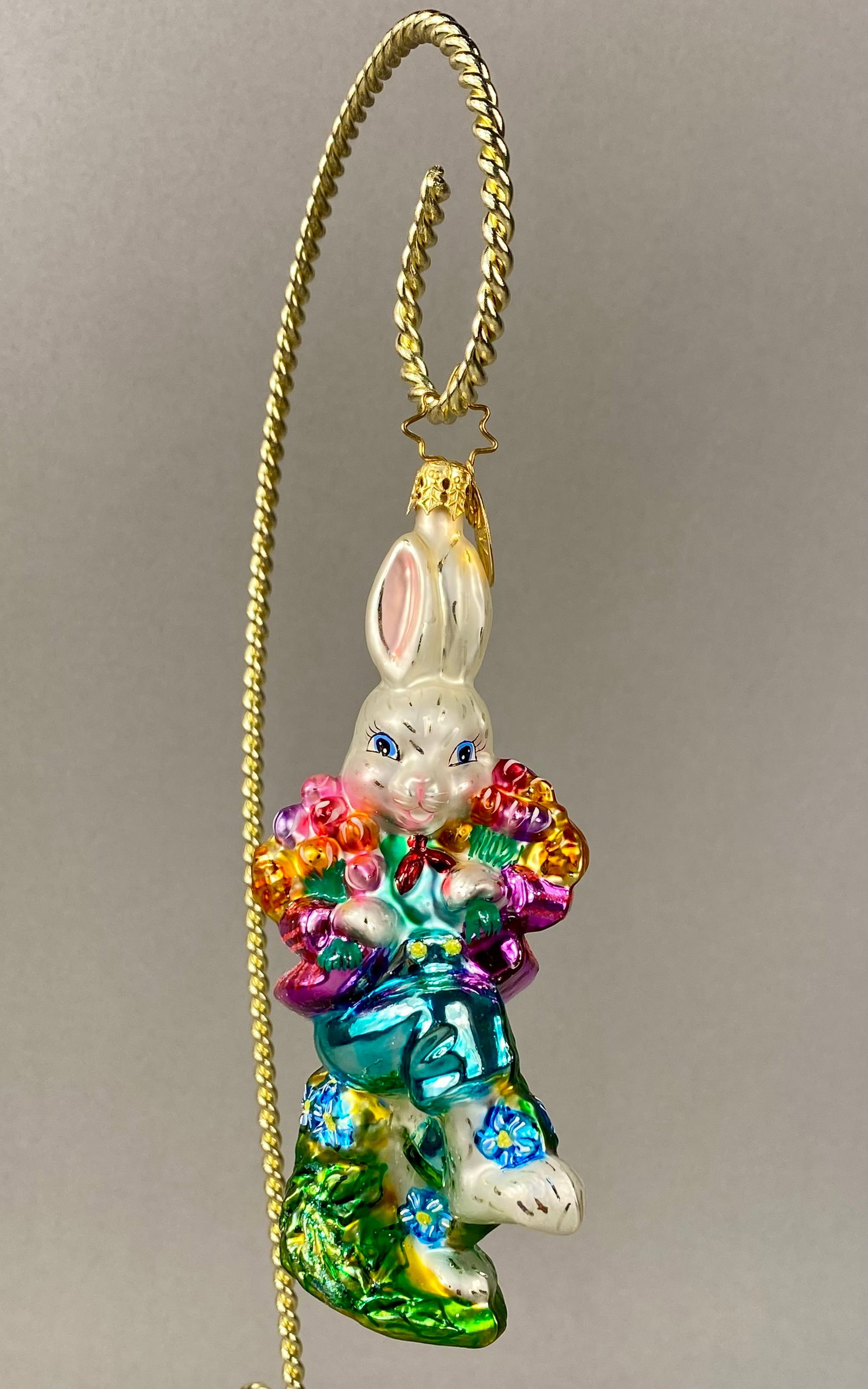 Christopher Radko Mouth-Blown Glass Rabbit with Flower Bouquet Ornament: This is a mouth-blown, hand-painted glass ornament by Christopher Radko. The ornament depicts a standing rabbit with a pearlescent white finish, blue eyes, and pink inner ears. The figure is dressed i