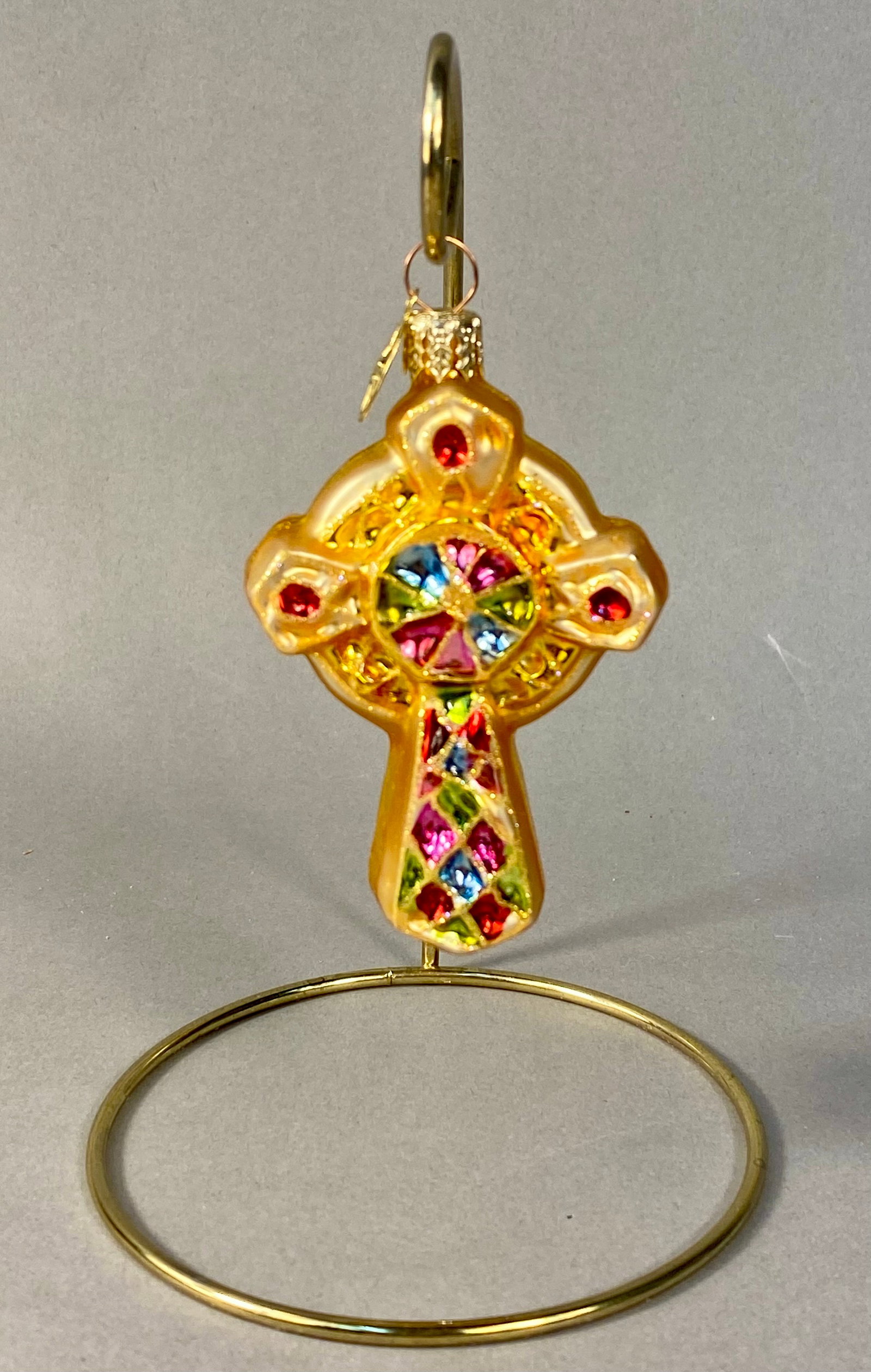 Christopher Radko Brilliant Bejeweled Cross Gem Glass Ornament: A mouth-blown glass holiday ornament by Christopher Radko, identified as the Brilliant Bejeweled Cross Gem pattern. The ornament is shaped as a Celtic cross with a translucent amber-gold glass body. T