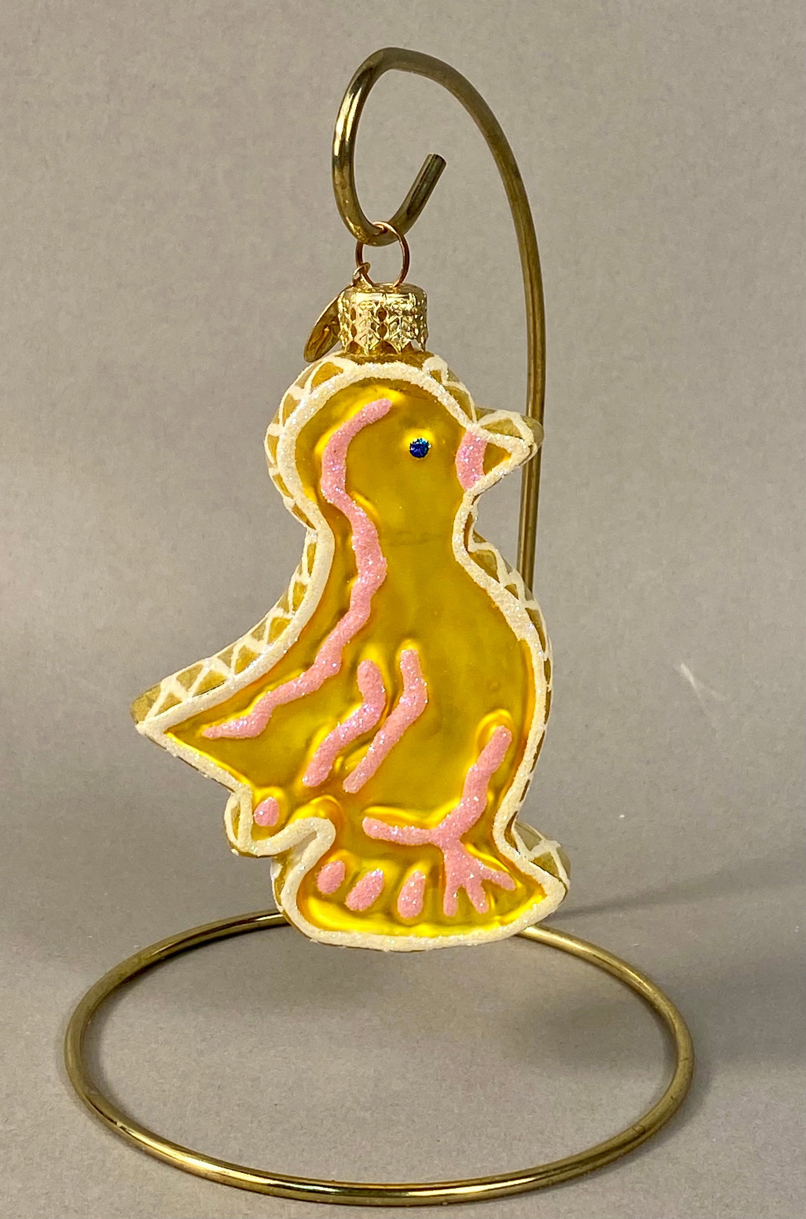 Christopher Radko Hand-Painted Glass Bird Christmas Ornament: A hand-blown glass Christmas ornament produced by Christopher Radko, featuring a stylized bird or duckling form. The piece is finished in a bright yellow translucent lacquer and decorated with pink gl