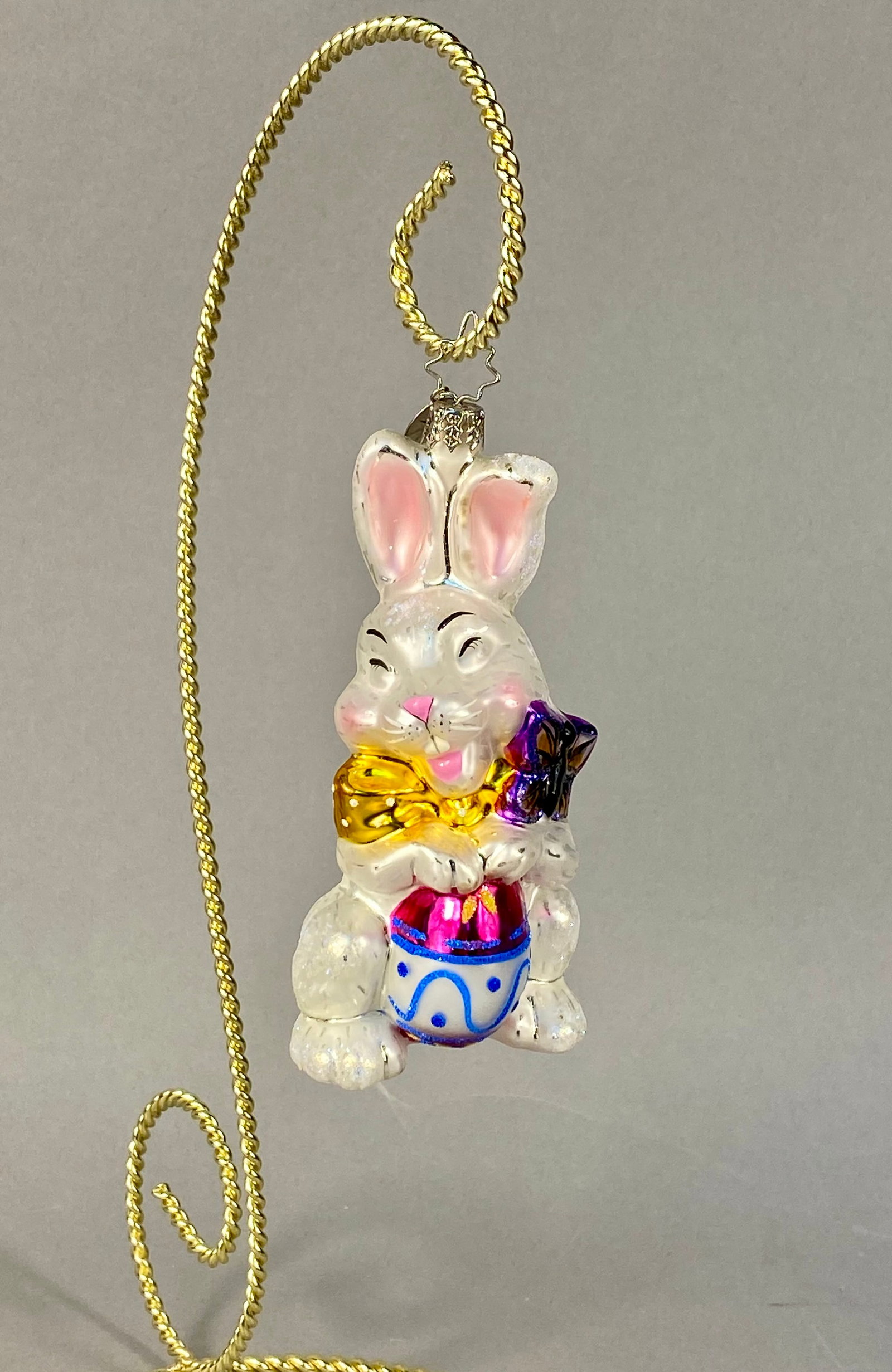 Christopher Radko Billy Bunny Goes Shopping Glass Easter Ornament: Christopher Radko mouth-blown glass holiday ornament identified as Billy Bunny Goes Shopping. This hand-painted figurine depicts a seated white rabbit embellished with iridescent glitter accents on it