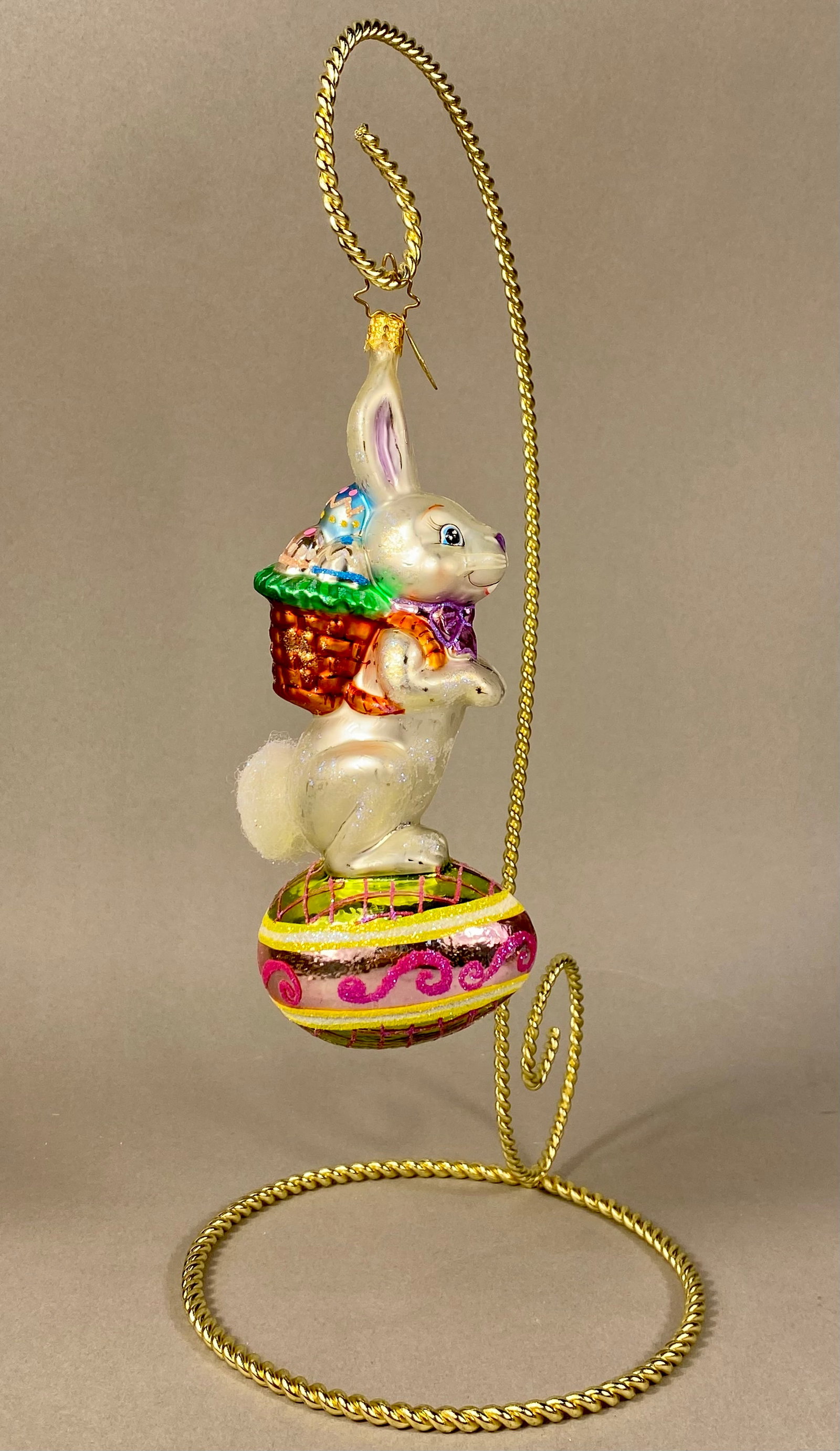 Christopher Radko Billy Bunny Goes Shopping Glass Ornament: A mouth-blown glass holiday ornament produced by Christopher Radko, titled Billy Bunny Goes Shopping. The ornament features a standing rabbit with a pearlescent white finish positioned atop a large, d