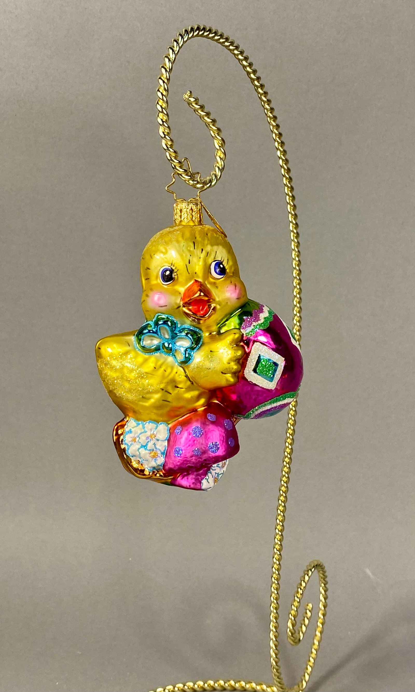 Christopher Radko Dapper Duckling Hand-Painted Glass Easter Ornament: This collectible mouth-blown glass holiday ornament is a Christopher Radko production titled Dapper Duckling. The piece depicts a whimsical yellow chick standing on a base of white and blue flowers. T