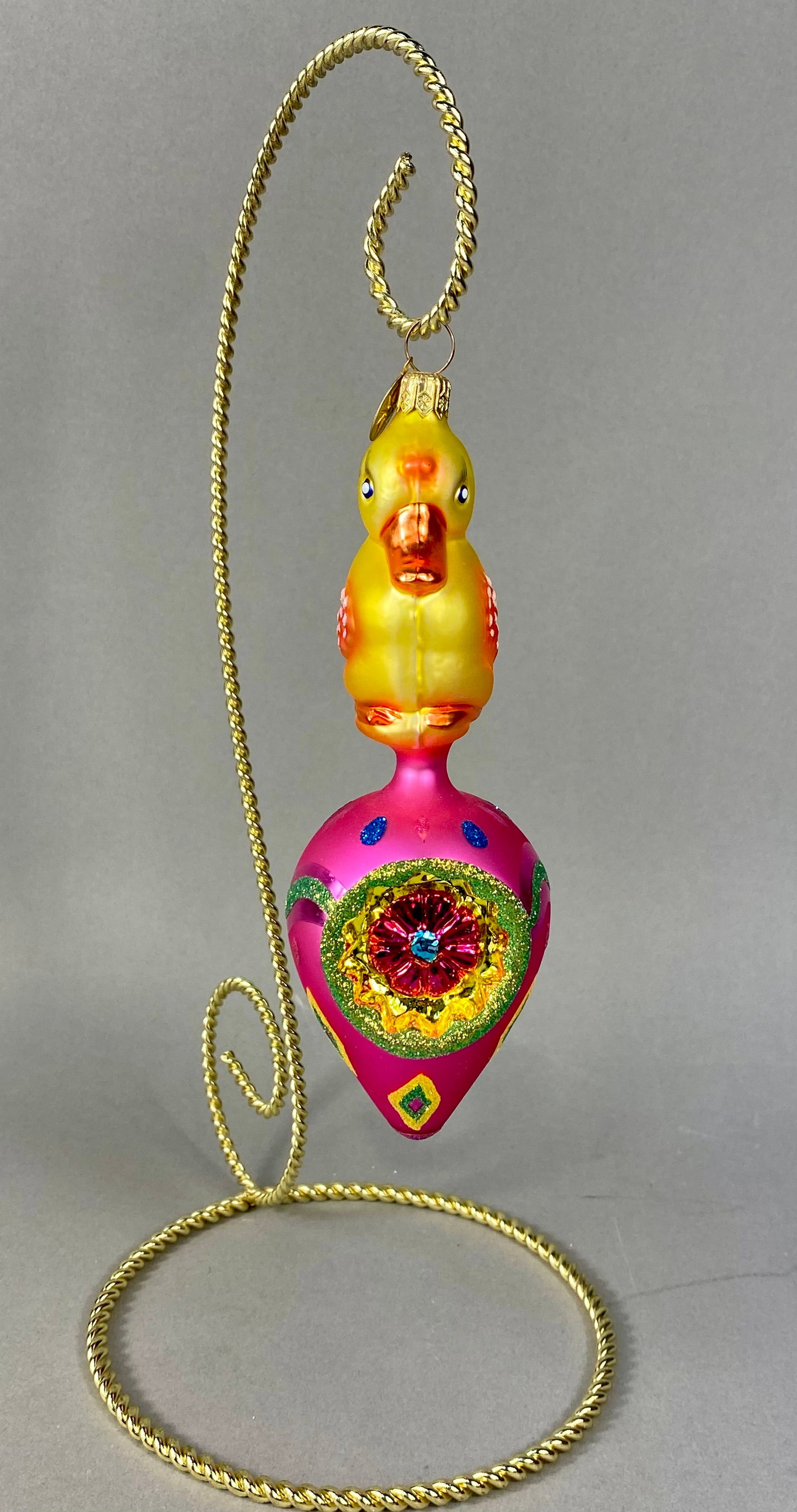 Christopher Radko Eggs and Quakers Mouth-Blown Glass Bird Ornament: This mouth-blown glass figural ornament is a Christopher Radko creation from the Eggs and Quakers collection. The piece features a hand-painted yellow chick with an orange beak and feet, blue eyes, an