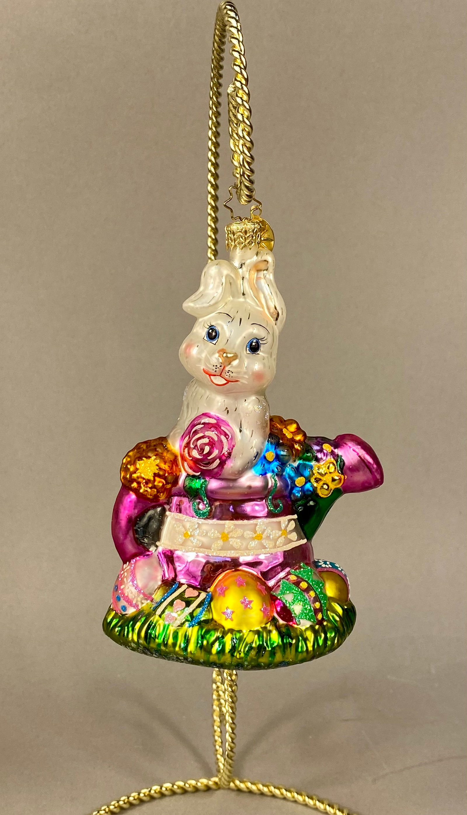 Christopher Radko Billy Bunny Goes Shopping Glass Easter Ornament: This mouth-blown and hand-painted glass ornament is titled Billy Bunny Goes Shopping by Christopher Radko. The piece depicts a white Easter bunny seated within a vibrant magenta watering can filled wi
