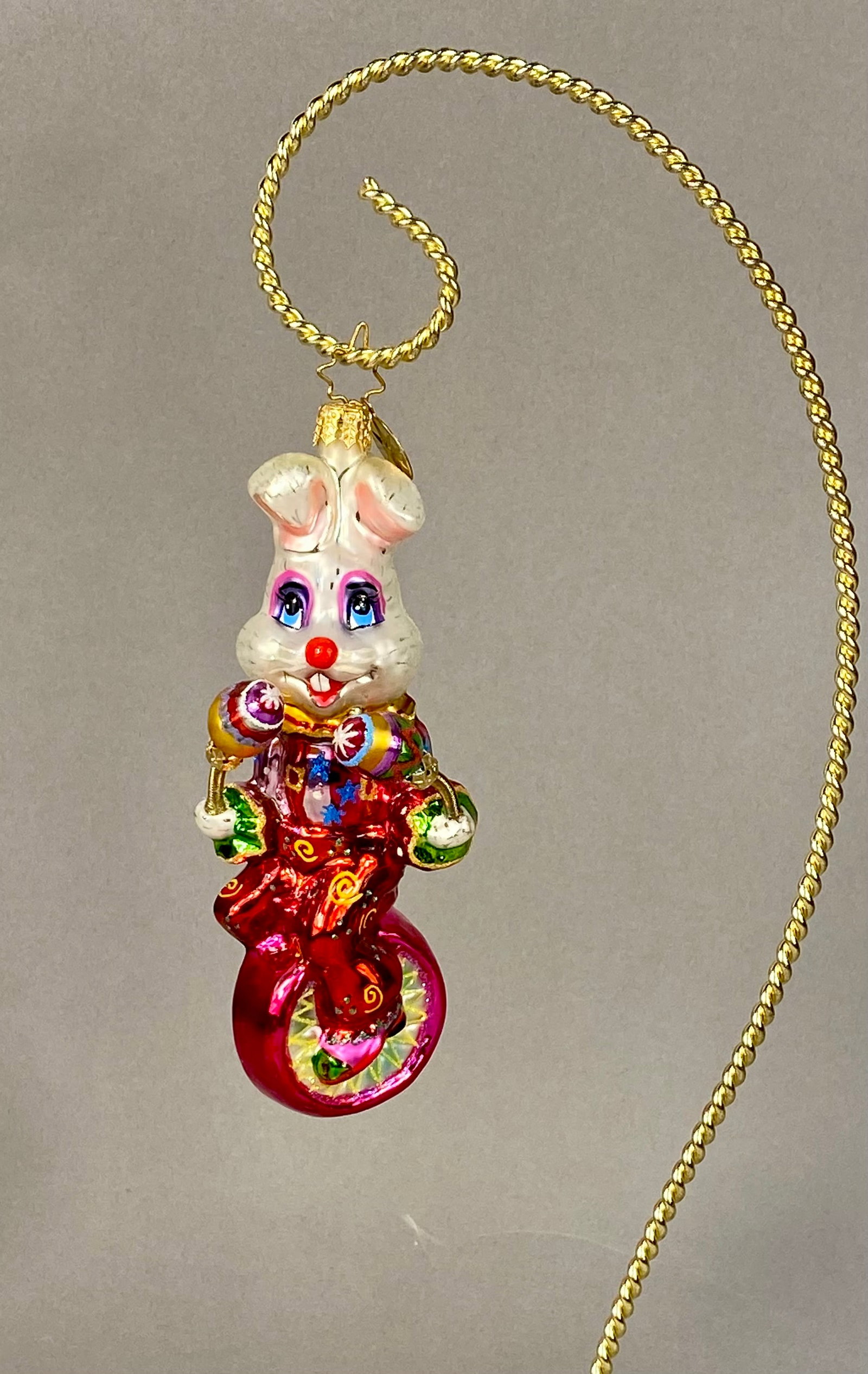 Christopher Radko Blown Glass Rabbit on Unicycle Holiday Ornament: A mouth-blown glass holiday ornament by Christopher Radko depicting an anthropomorphic white rabbit circus performer riding a unicycle. The figure is hand-painted with brilliant lacquers and finished 