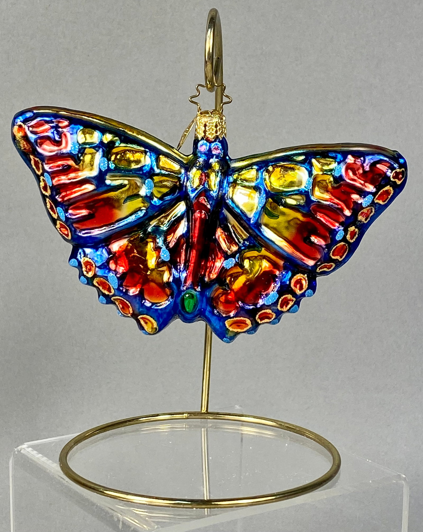 Christopher Radko Hand-Painted Glass Butterfly Ornament: This hand-blown glass butterfly ornament is an authentic piece by Christopher Radko. The item features a vibrant, multi-colored butterfly with spread wings, created using traditional European mouth-bl