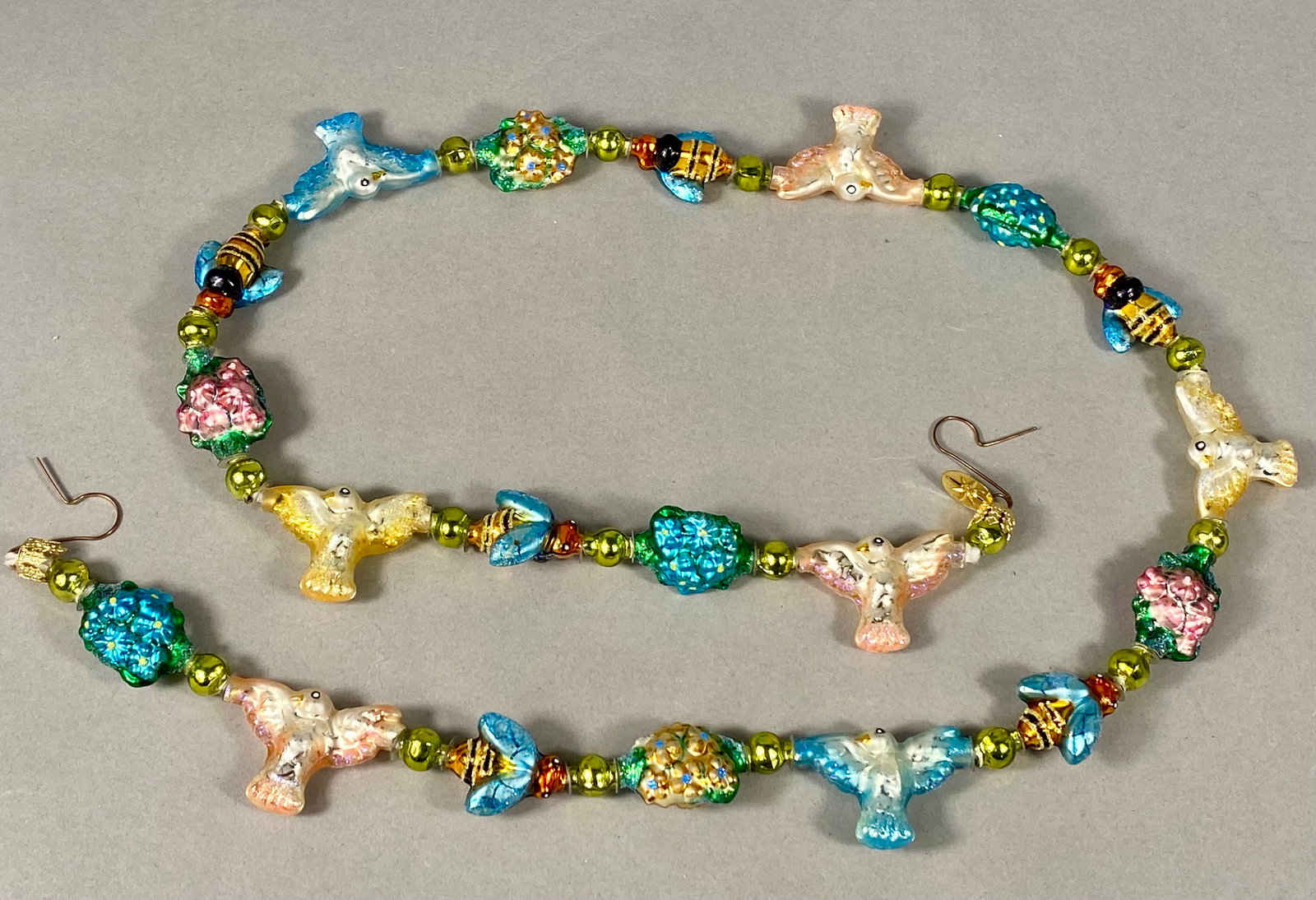 Christopher Radko Wings of Spring Glass Bead Garland: A Christopher Radko Wings of Spring glass bead garland featuring a sequence of mouth-blown and hand-painted glass charms. The decorative charms include birds in blue, yellow, and pink hues, bumblebees