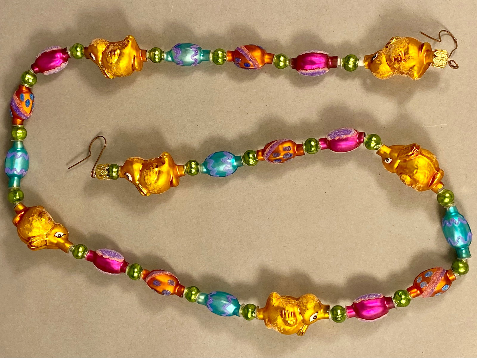 Springburst Beaded Decorative Garland with Butterfly and Starburst Motifs: This decorative beaded garland is identified as a Springburst Garland by the label on its original retail packaging. The strand consists of multi-colored glass and plastic beads strung on a gold-tone 