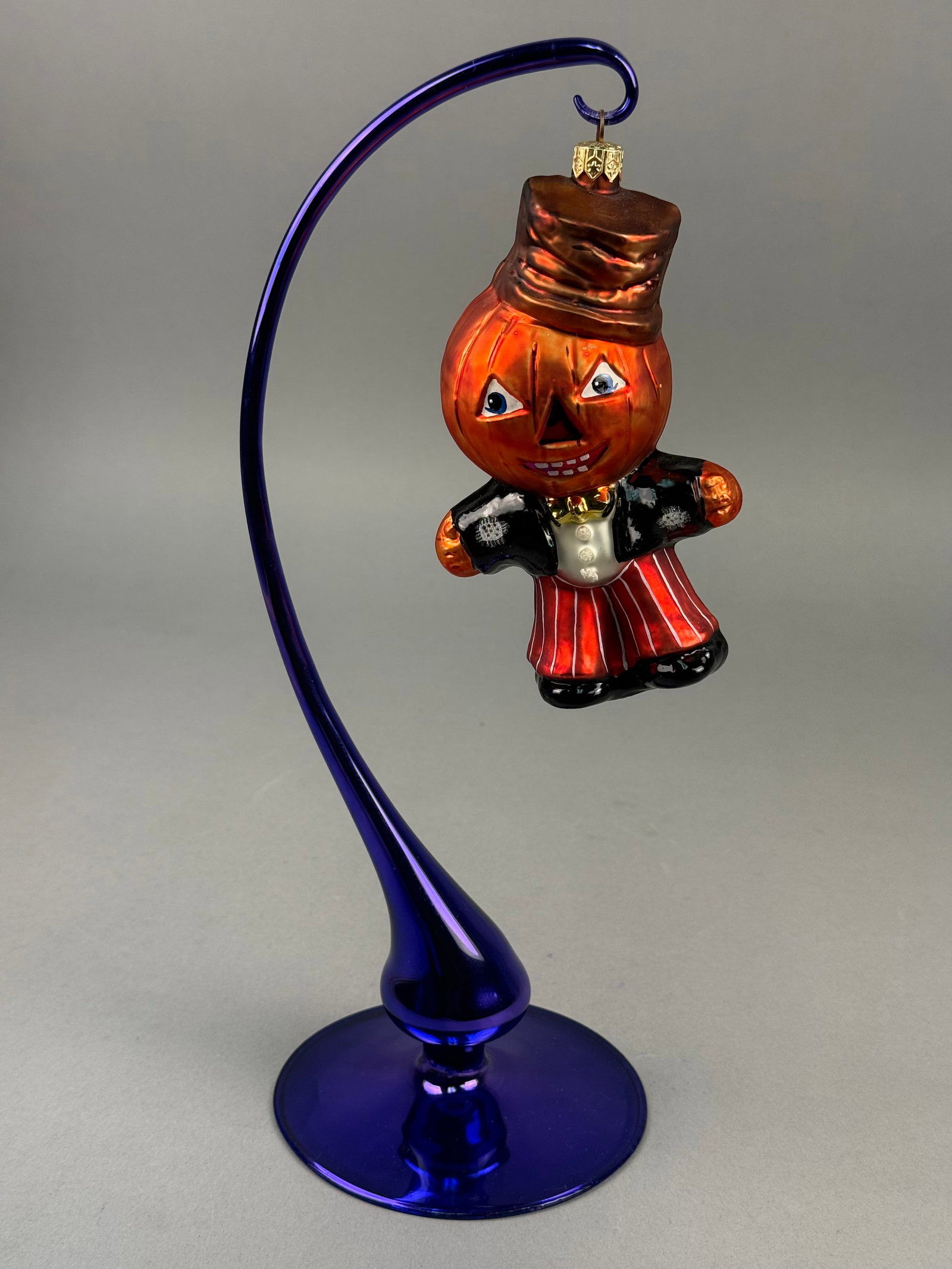 Radko Jest Jack Glass Halloween Ornament: This is a contemporary hand blown glass holiday ornament produced by Christopher Radko, specifically identified as the Jest Jack pattern. A gold-toned metal cap at the top is embossed with the letters