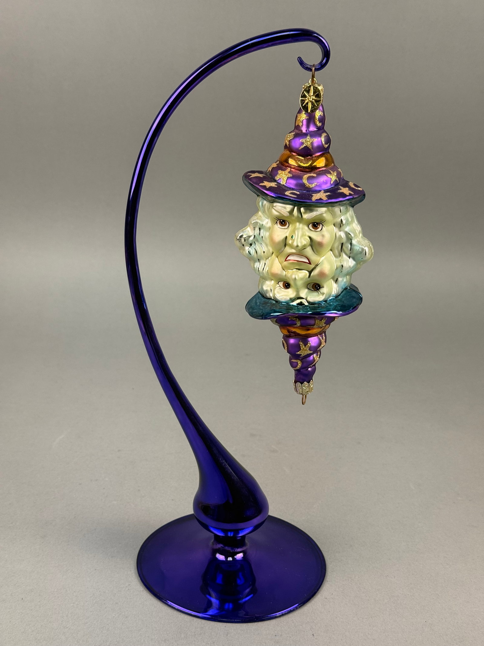 Radko Good Witch or Bad Witch Glass Ornament: A Christopher Radko mold-blown glass ornament titled Good Witch or Bad Witch The ornament features the signature Christopher Radko gold-toned metal cap embossed with a starburst pattern. Ornament hang