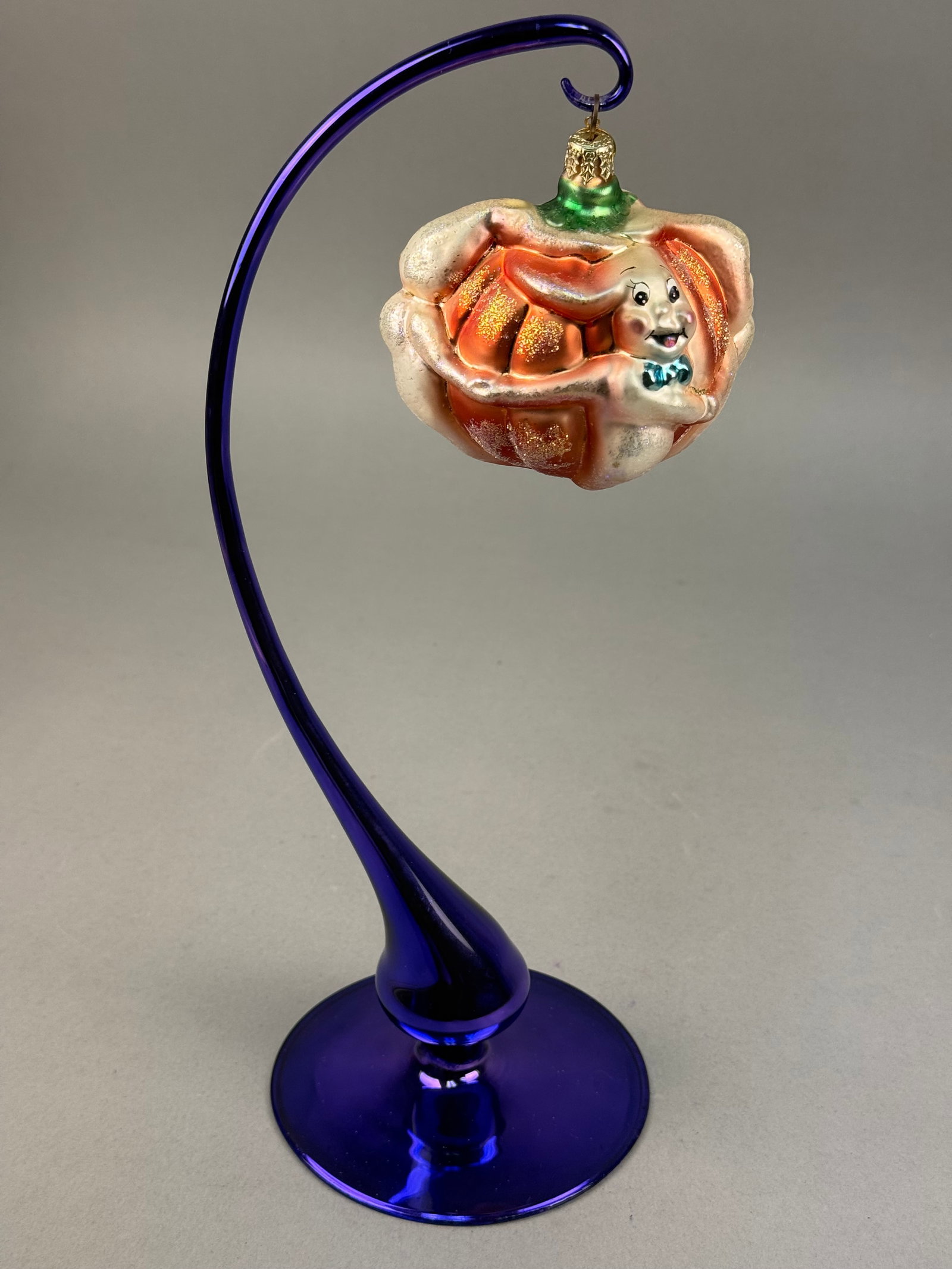 Radko Glass Halloween Pumpkin and Ghost Ornament: This mouth-blown glass holiday ornament is a hand-painted piece produced by Christopher Radko. The cap features an embossed starburst symbol, which is the trademark insignia for Christopher Radko orna